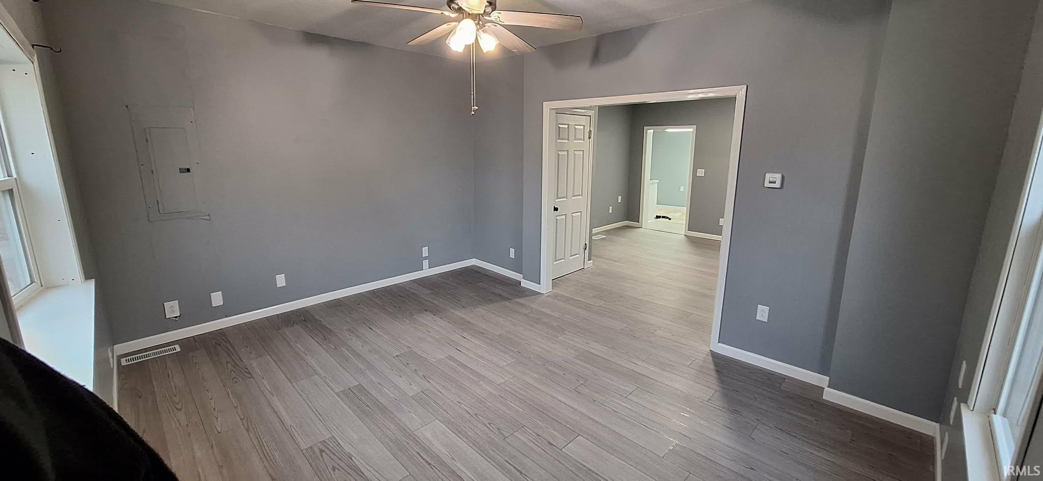 Empty room featuring ceiling fan, electric panel, and wood finished floors
