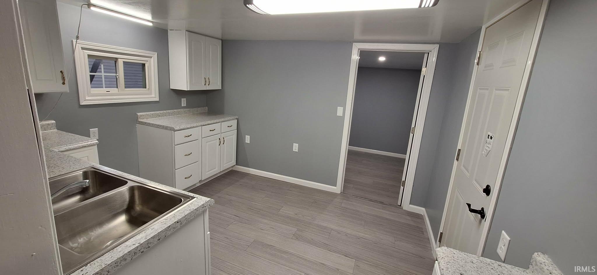 Kitchen featuring white cabinets, light countertops, and light wood-style flooring