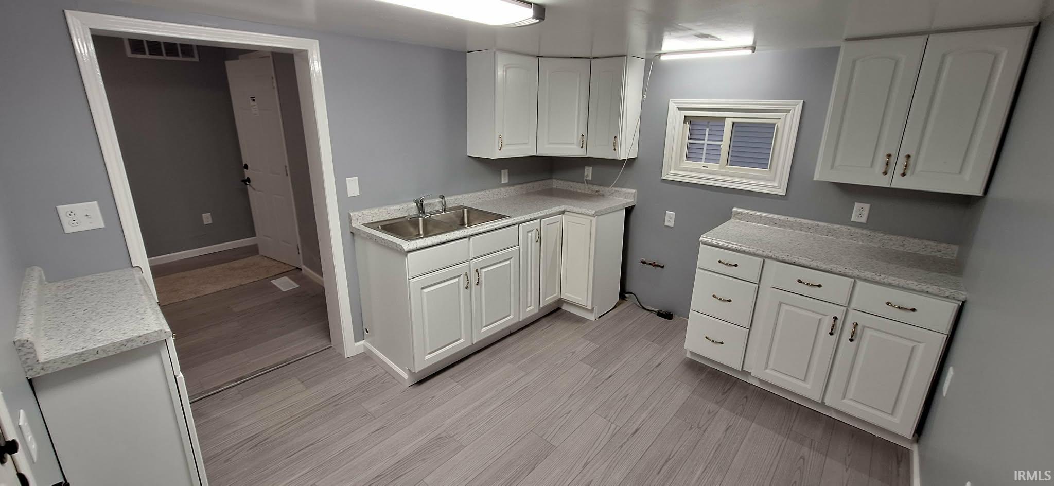 Kitchen featuring light countertops, white cabinets, and light wood-style floors