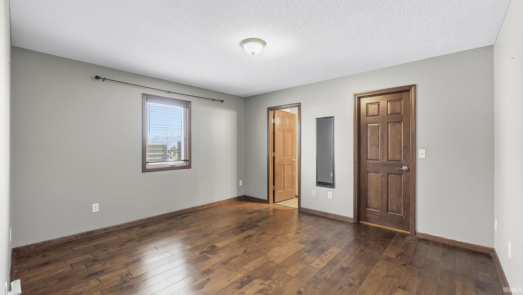 Unfurnished bedroom featuring a textured ceiling and dark wood finished floors