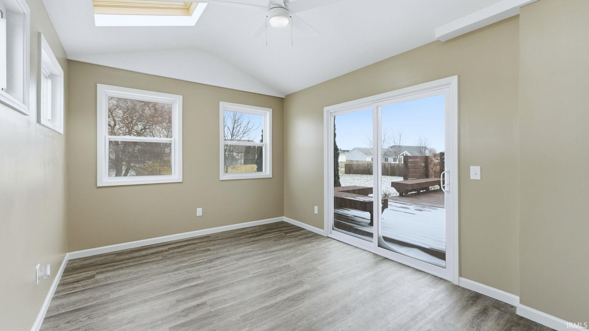 Empty room featuring lofted ceiling, light wood finished floors, and ceiling fan