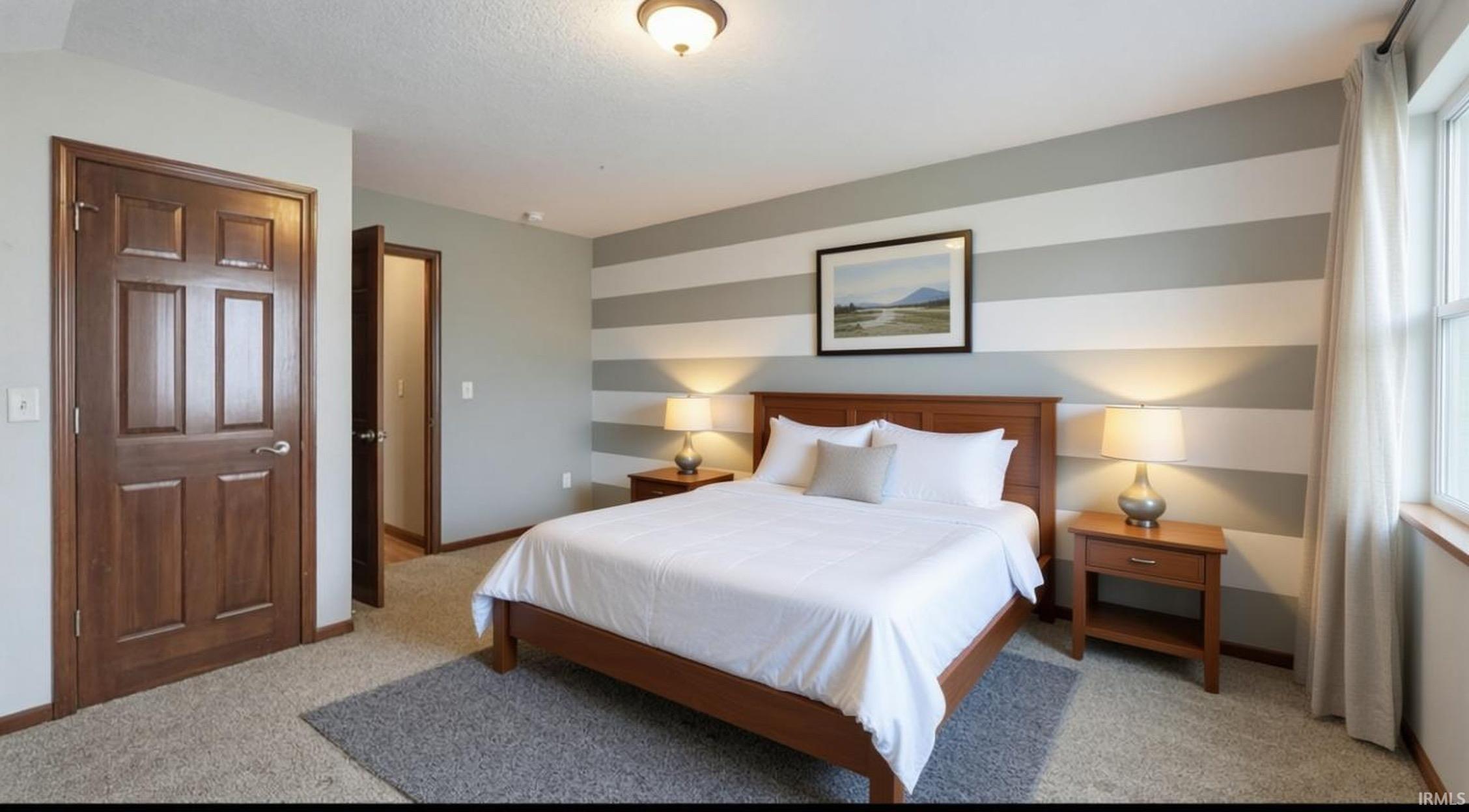 Bedroom with light colored carpet and an accent wall