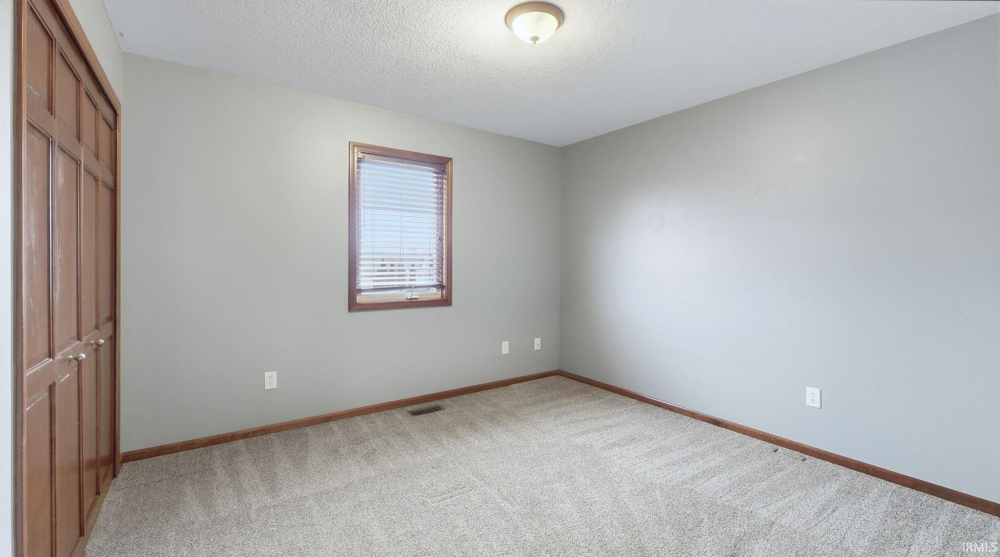 Unfurnished bedroom featuring a closet, a textured ceiling, and carpet flooring