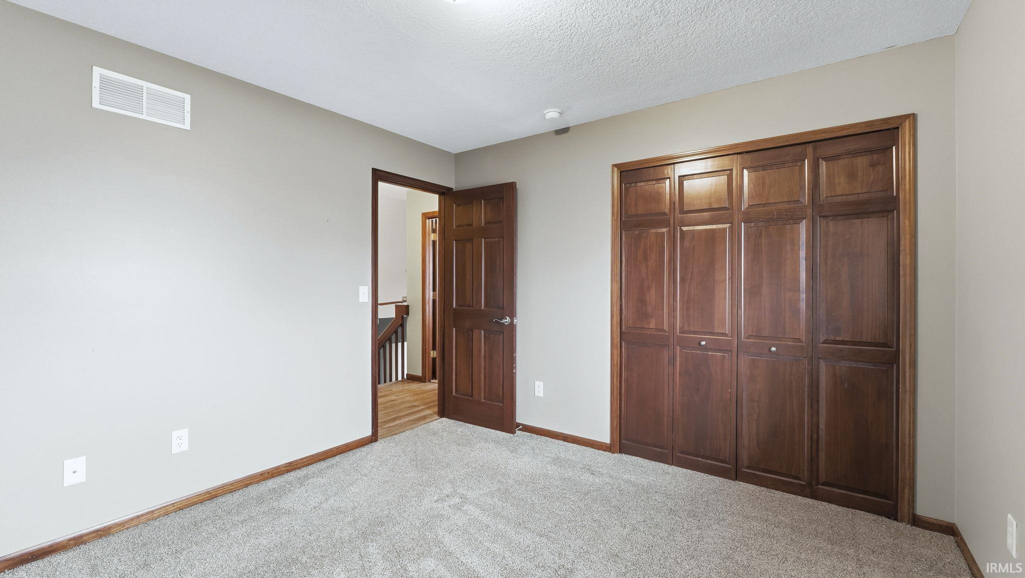Unfurnished bedroom with carpet flooring, a closet, and a textured ceiling
