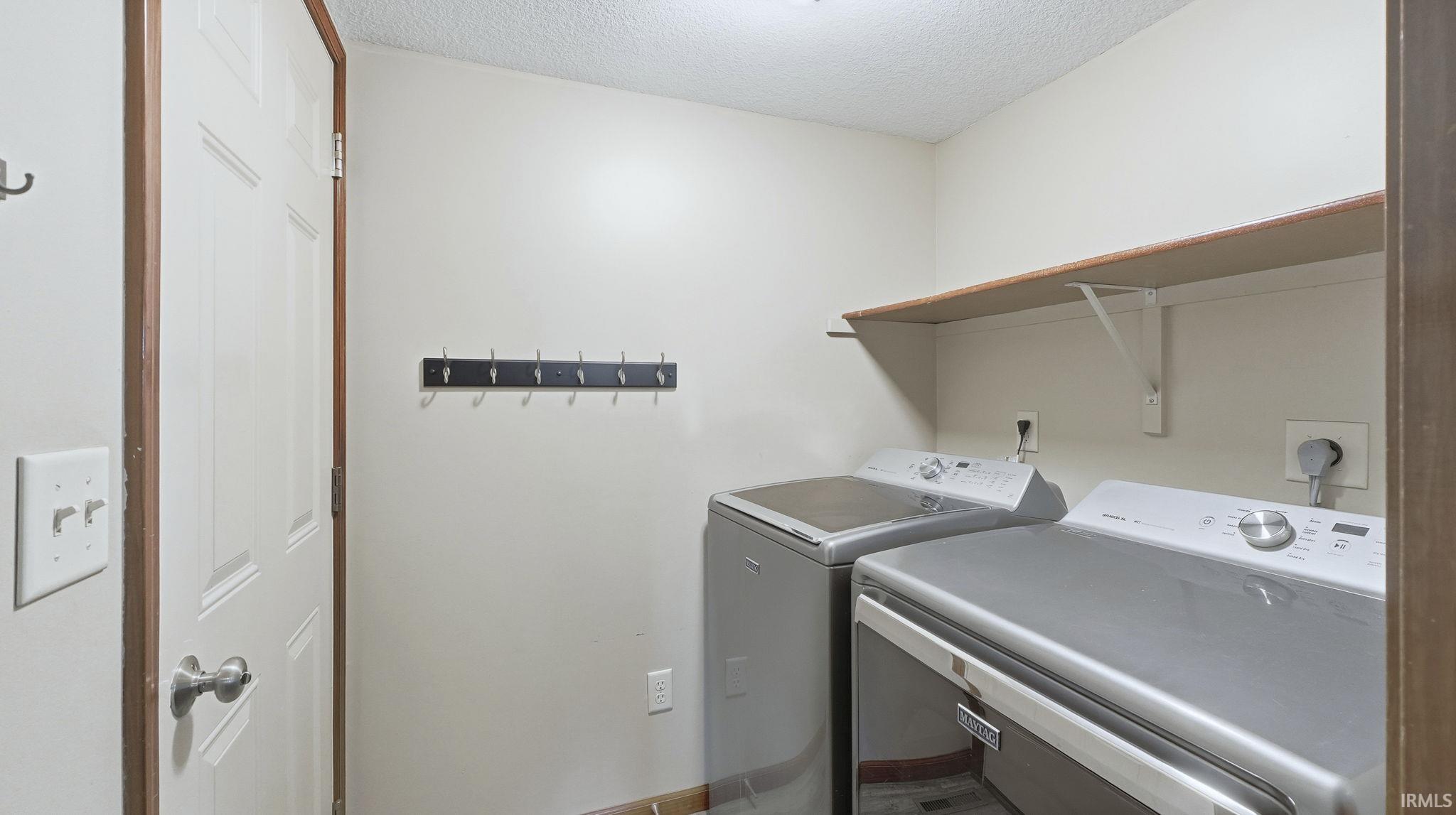 Washroom with a textured ceiling and independent washer and dryer