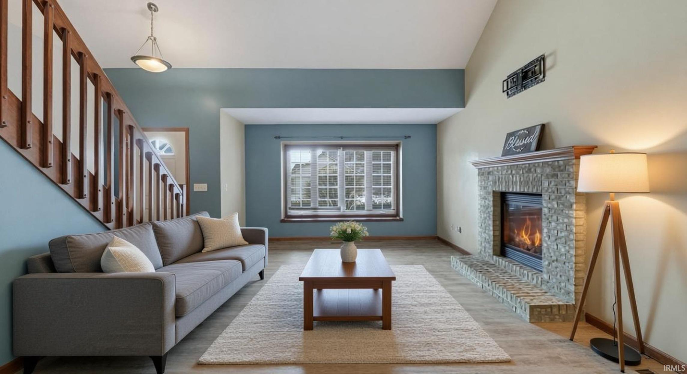 Living room with a fireplace, wood finished floors, and lofted ceiling
