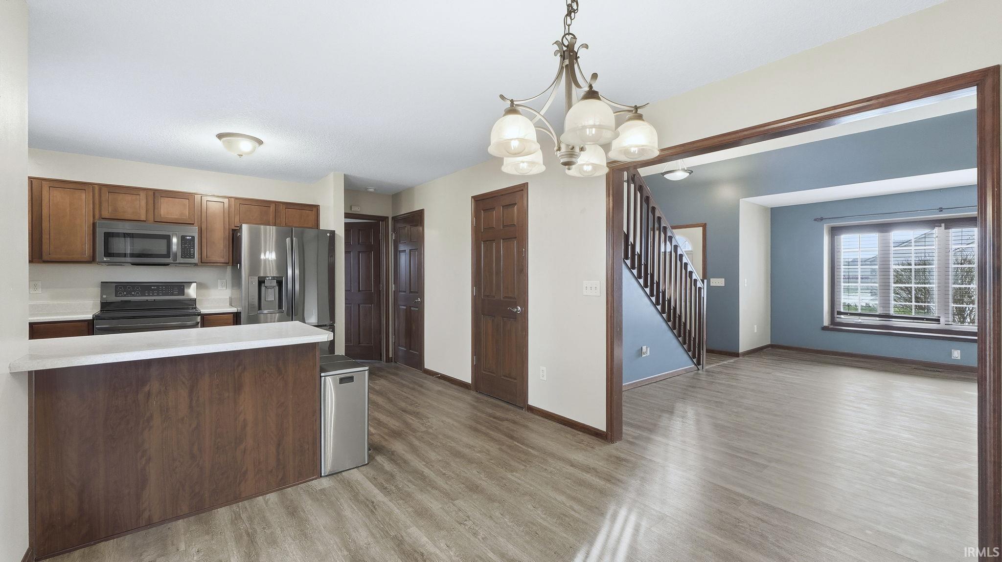Kitchen with light countertops, pendant lighting, stainless steel appliances, a peninsula, and a chandelier