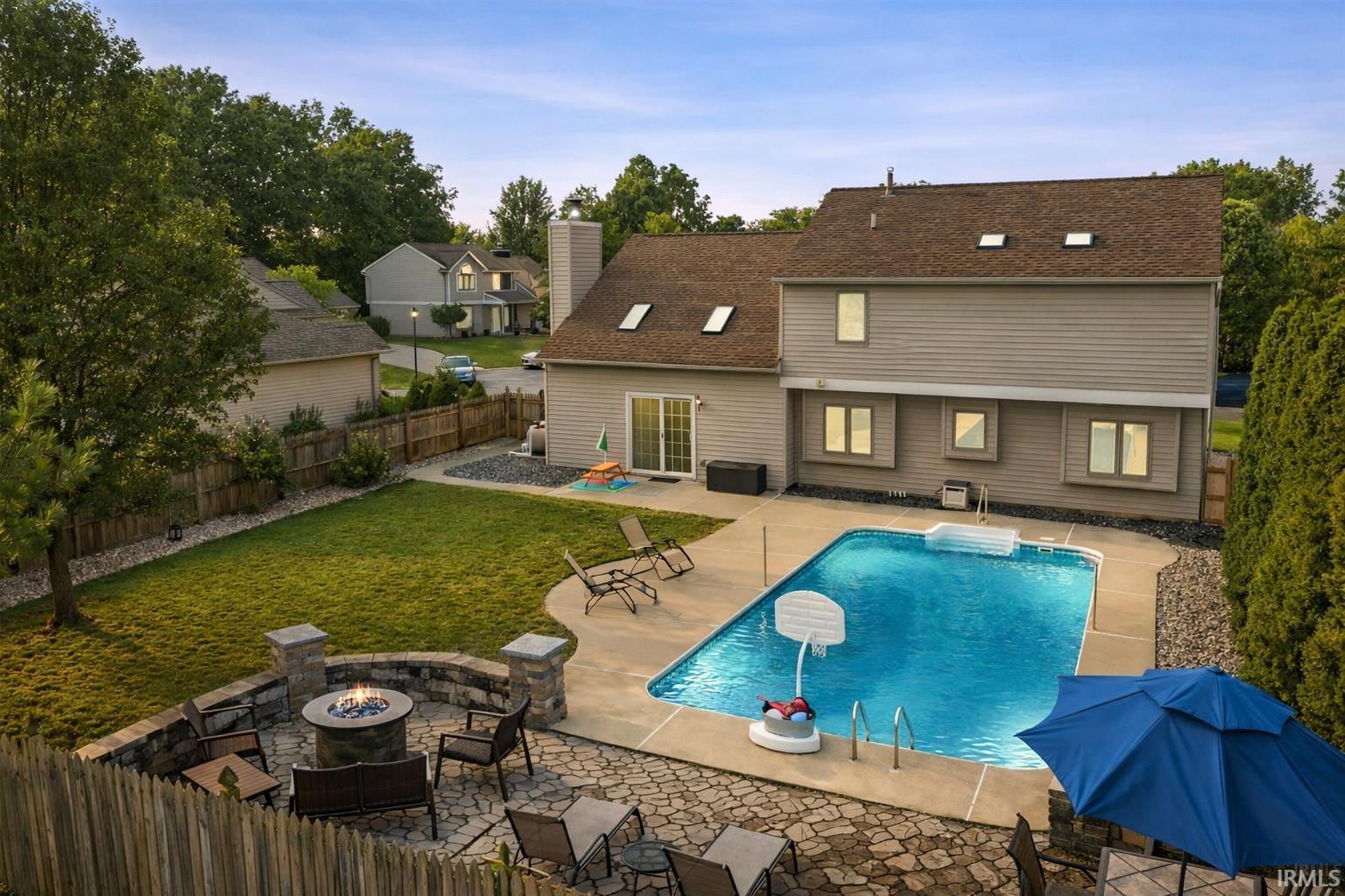 Rear view of property featuring a patio area, a fire pit, a fenced backyard, and roof with shingles
