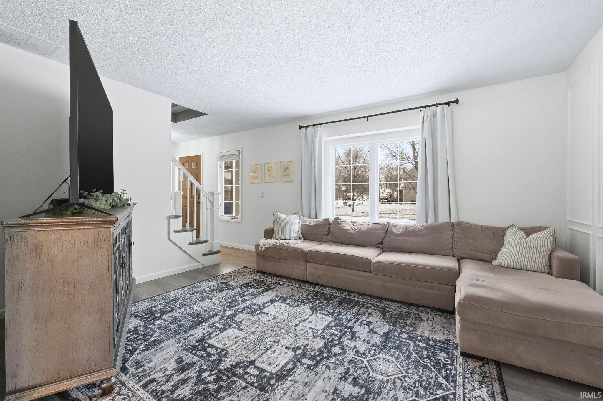 Living area featuring a textured ceiling, stairs, and wood finished floors