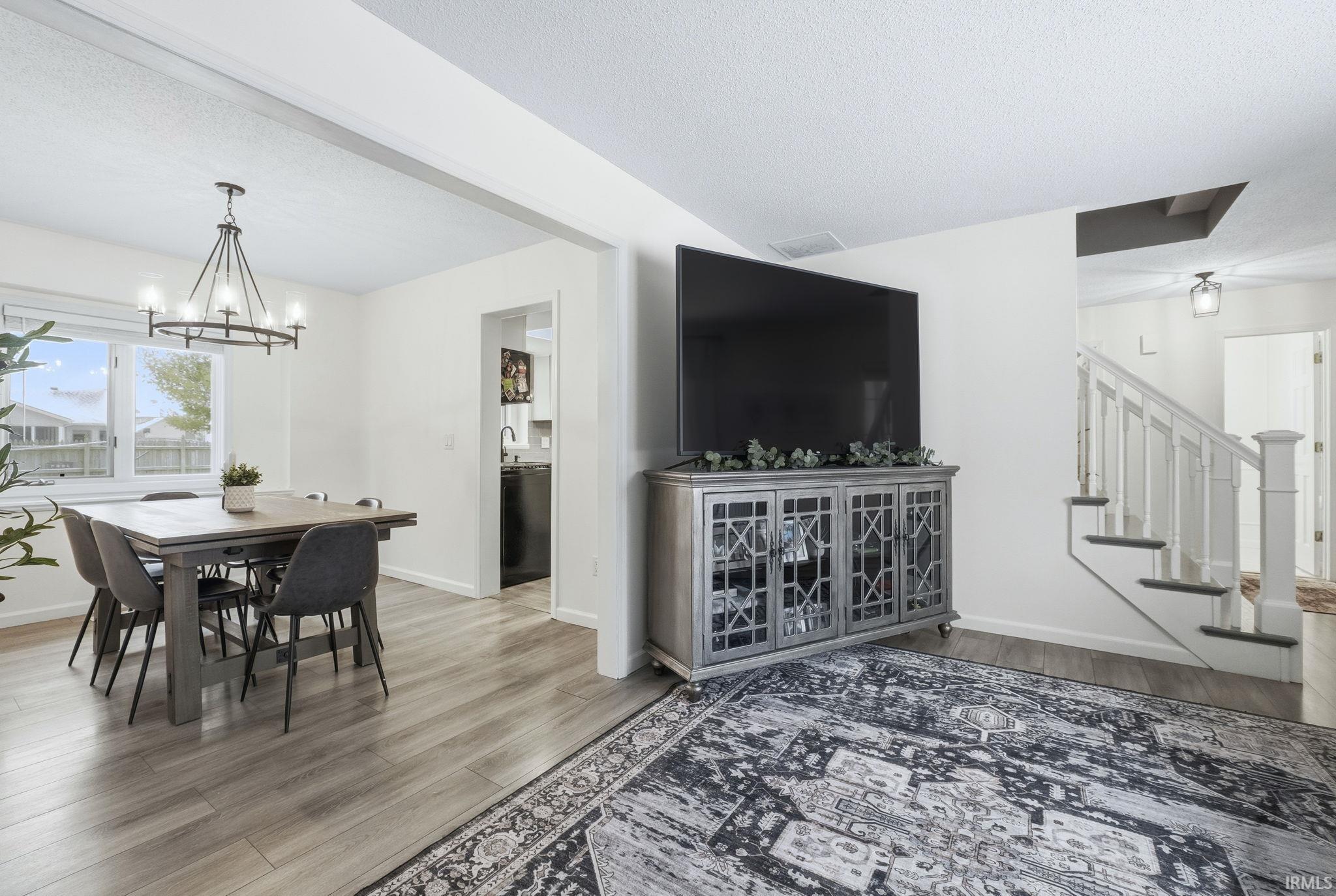 Dining room featuring stairway, light wood-style flooring, a textured ceiling, and a chandelier