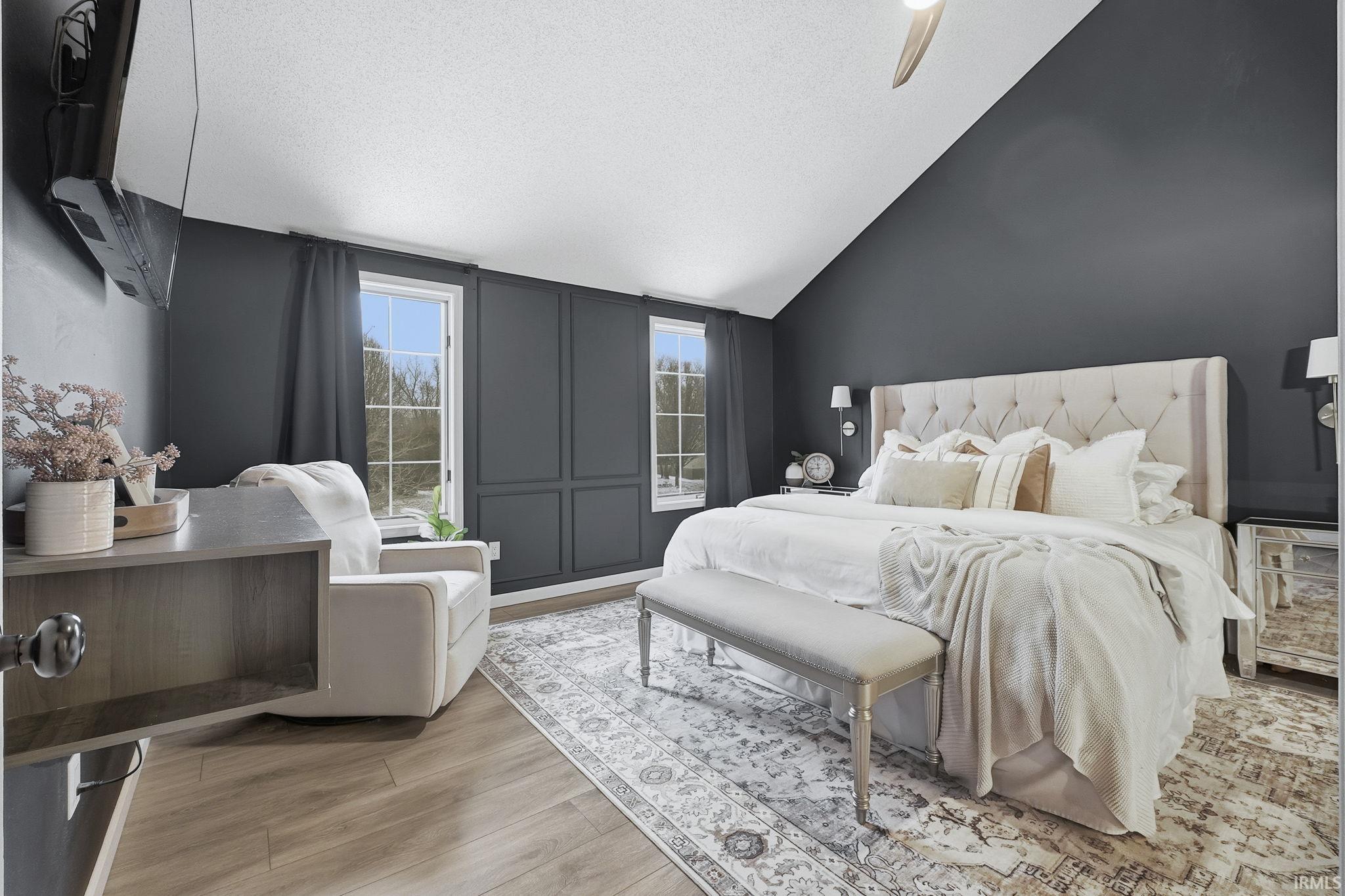 Bedroom featuring vaulted ceiling, a textured ceiling, light wood-style flooring, and ceiling fan