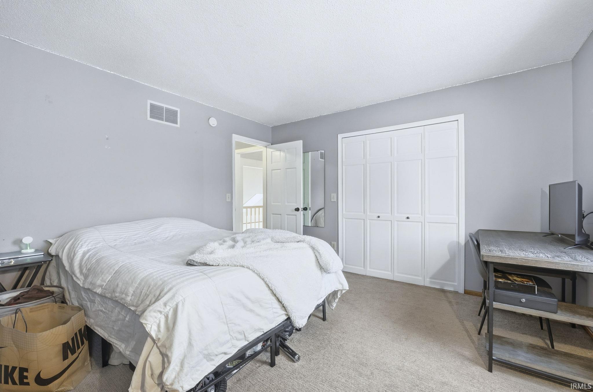 Carpeted bedroom with a closet and a textured ceiling