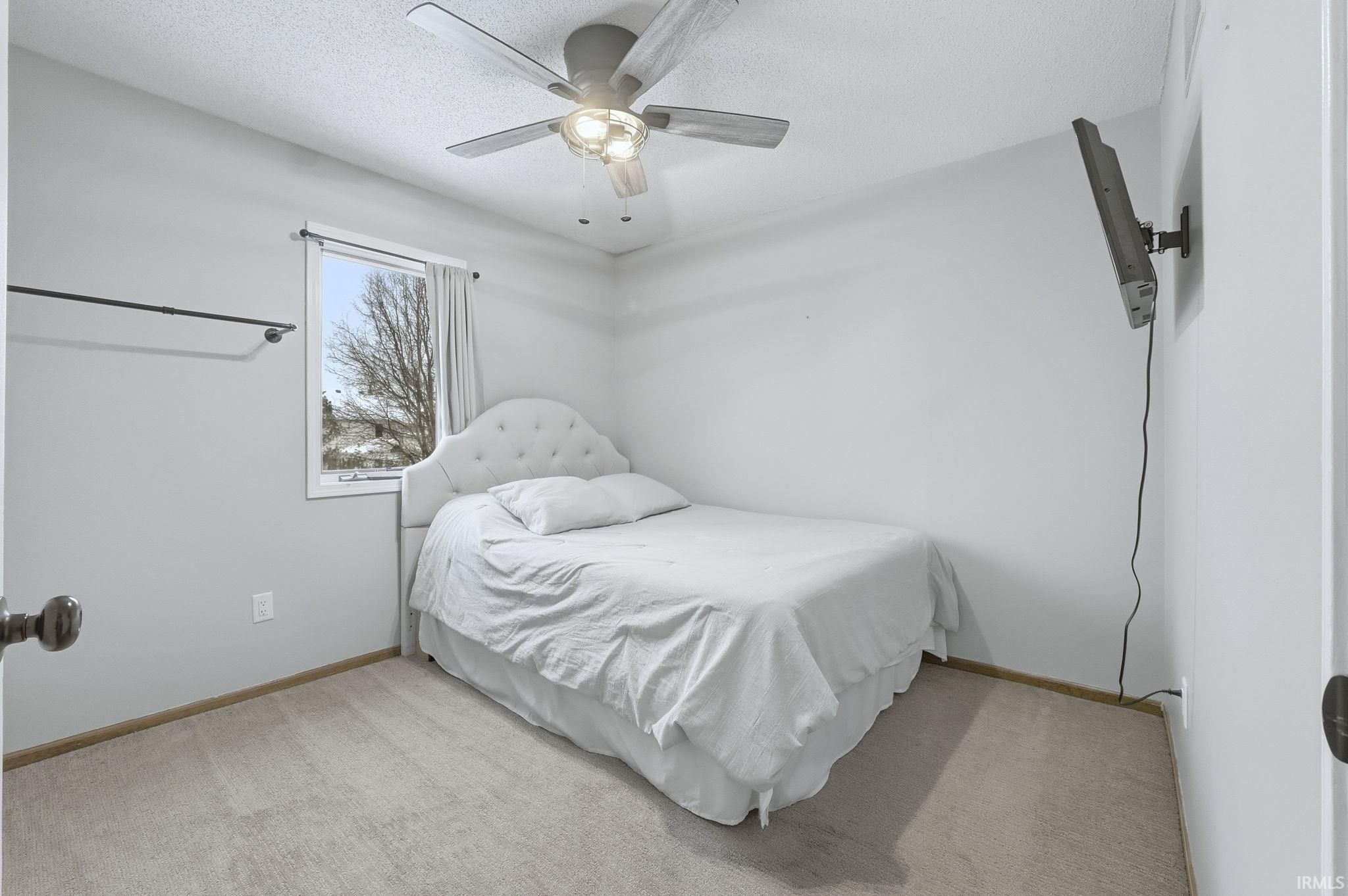 Bedroom featuring a ceiling fan, light carpet, and a textured ceiling