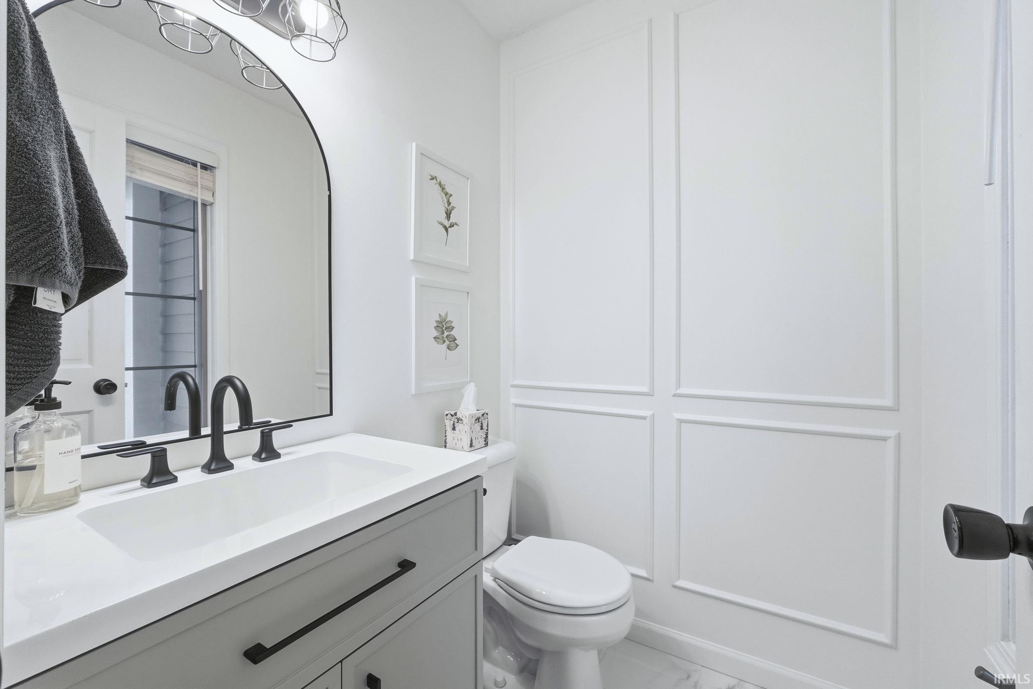 Half bath featuring vanity and marble look tiles