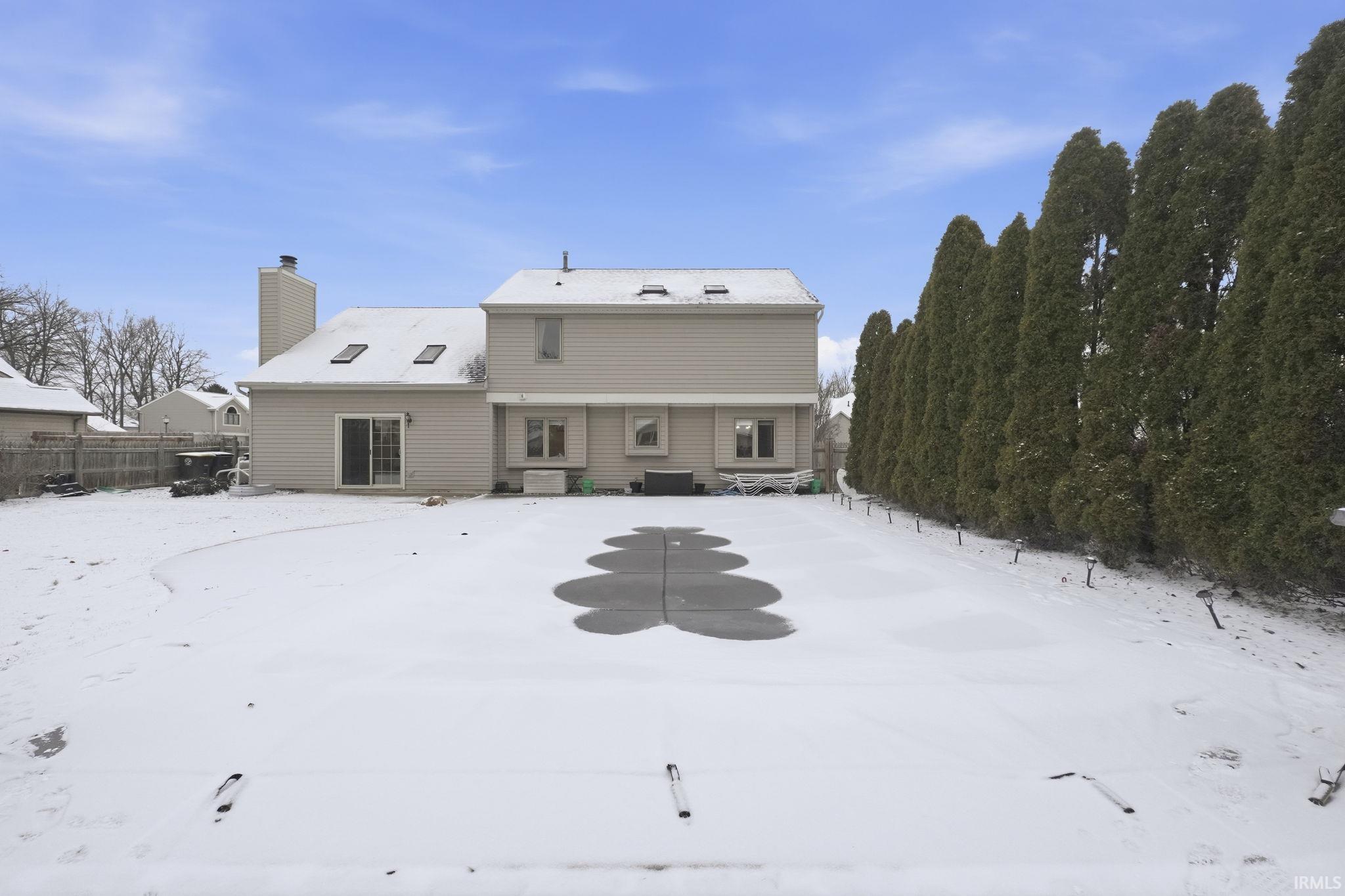 Snow covered rear of property featuring a chimney and a patio