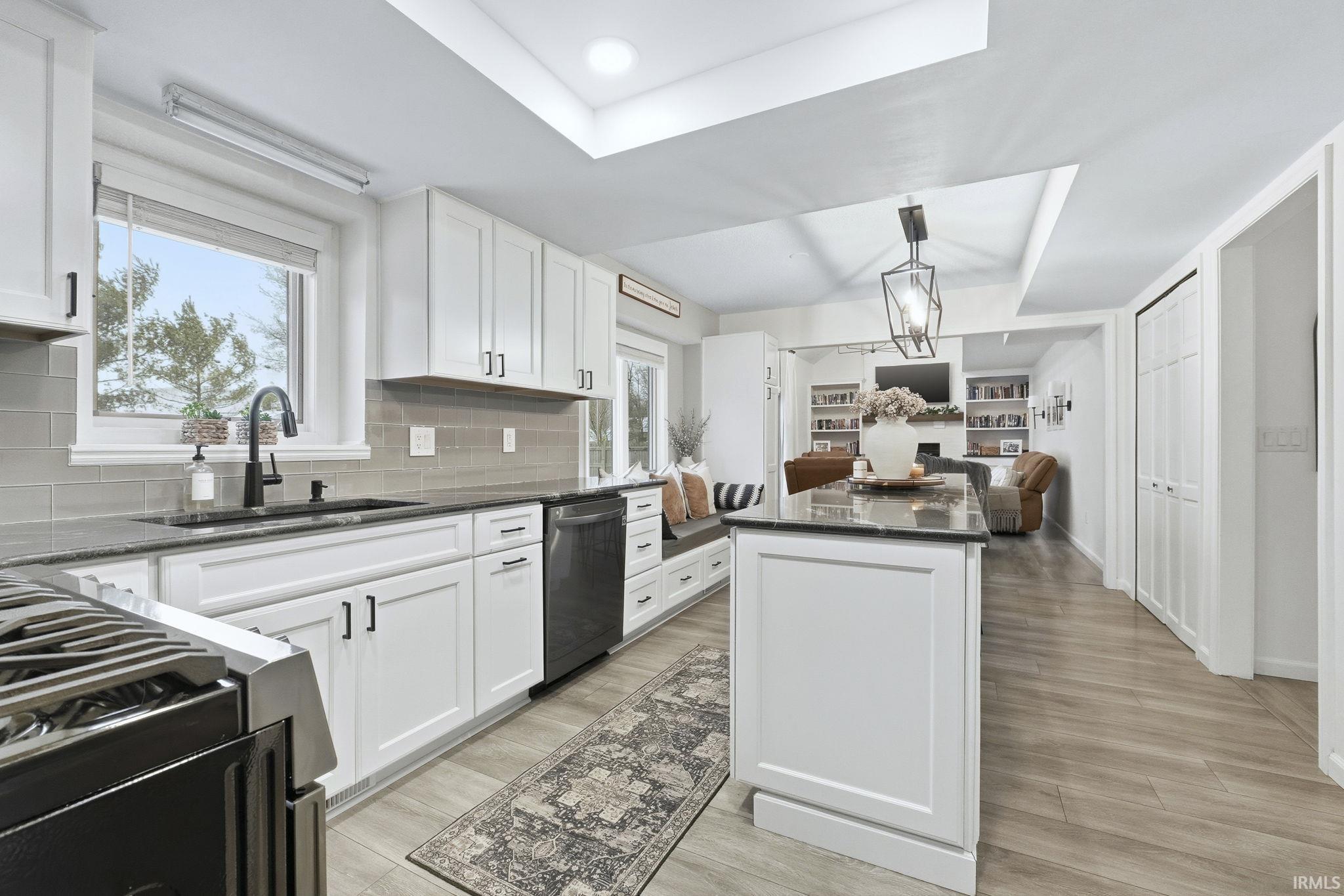 Kitchen featuring a raised ceiling, dark stone countertops, open floor plan, and gas stove