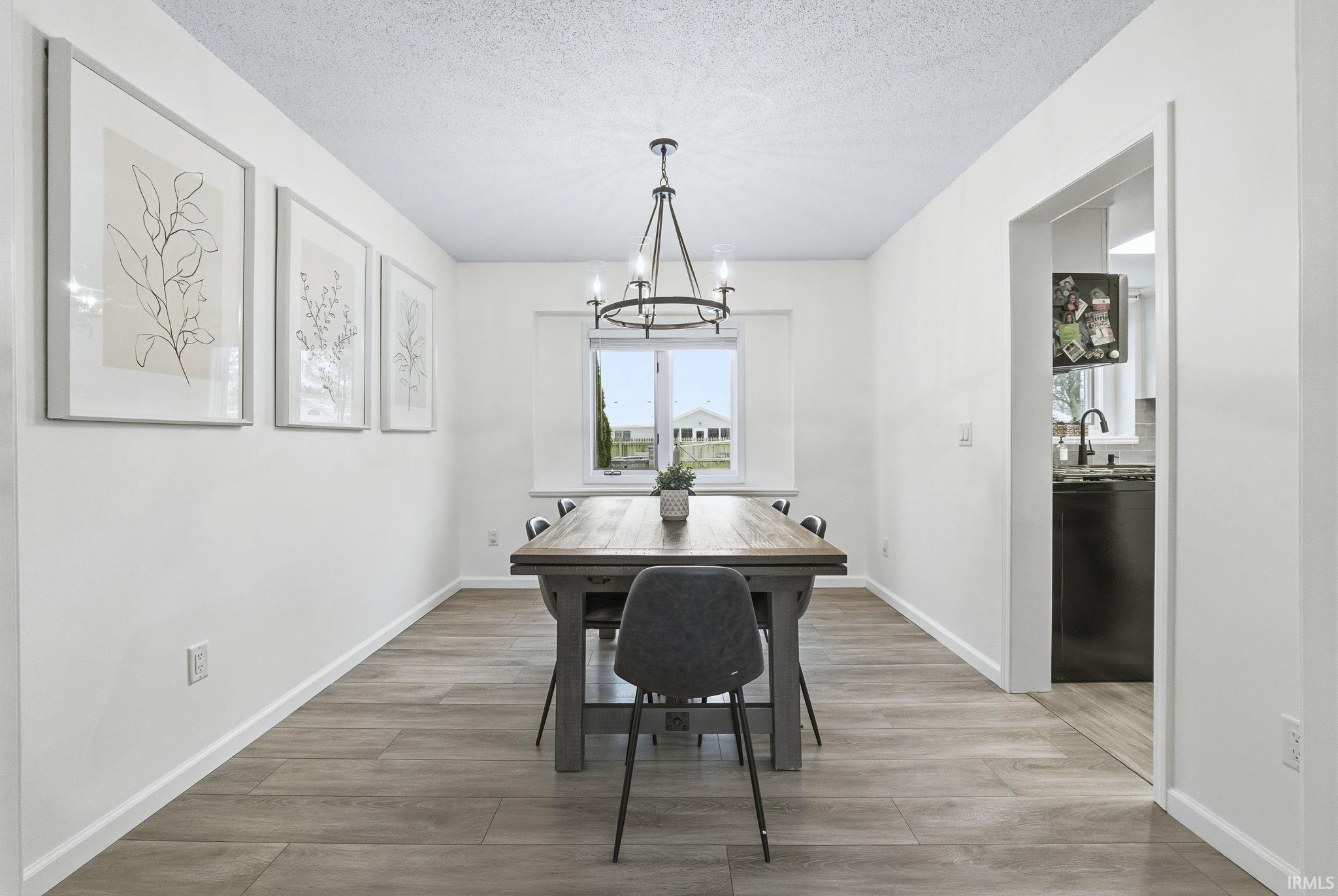 Dining space with light wood-type flooring, a chandelier, and a textured ceiling