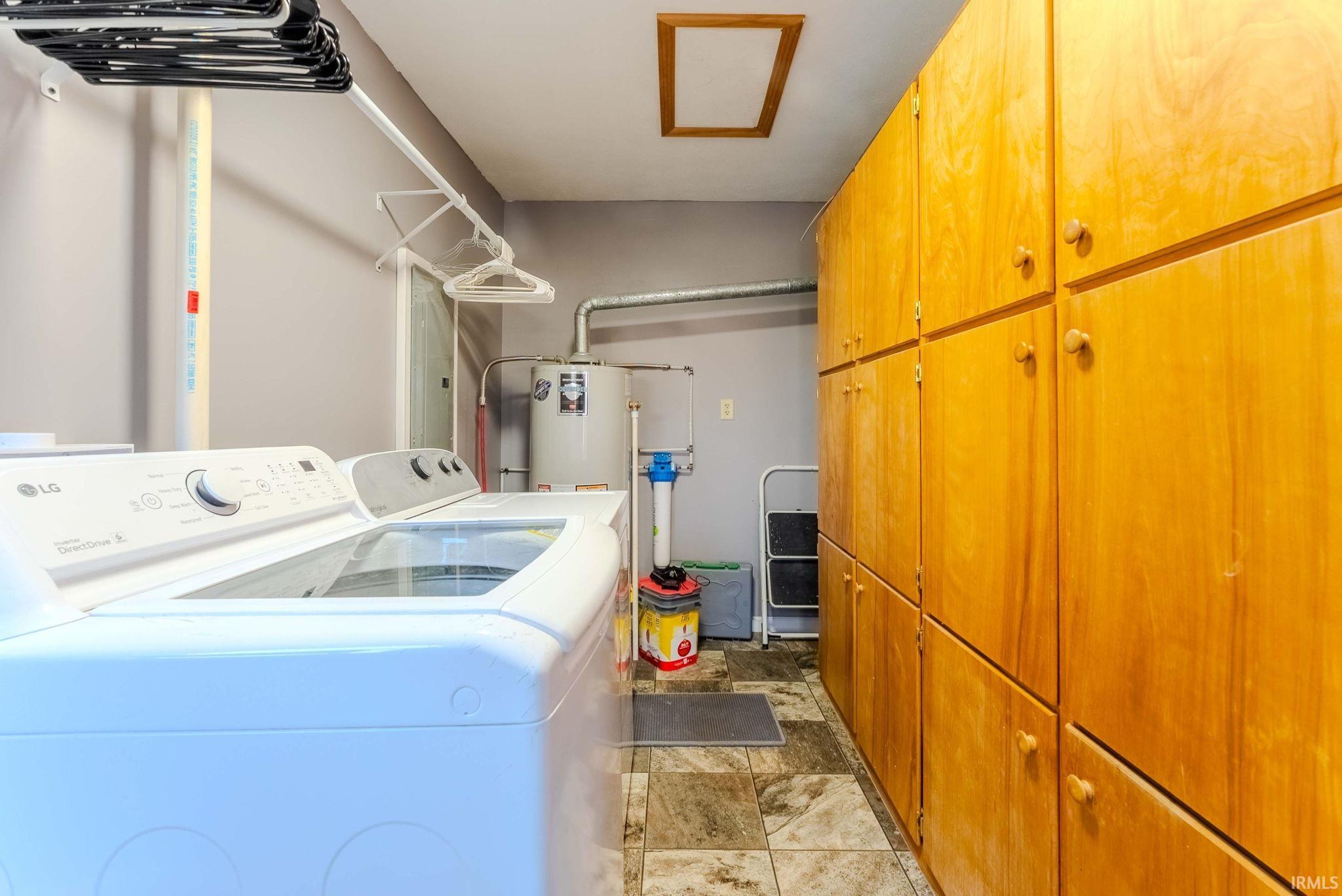 Laundry room featuring cabinet space, washing machine and clothes dryer, and stone finish flooring