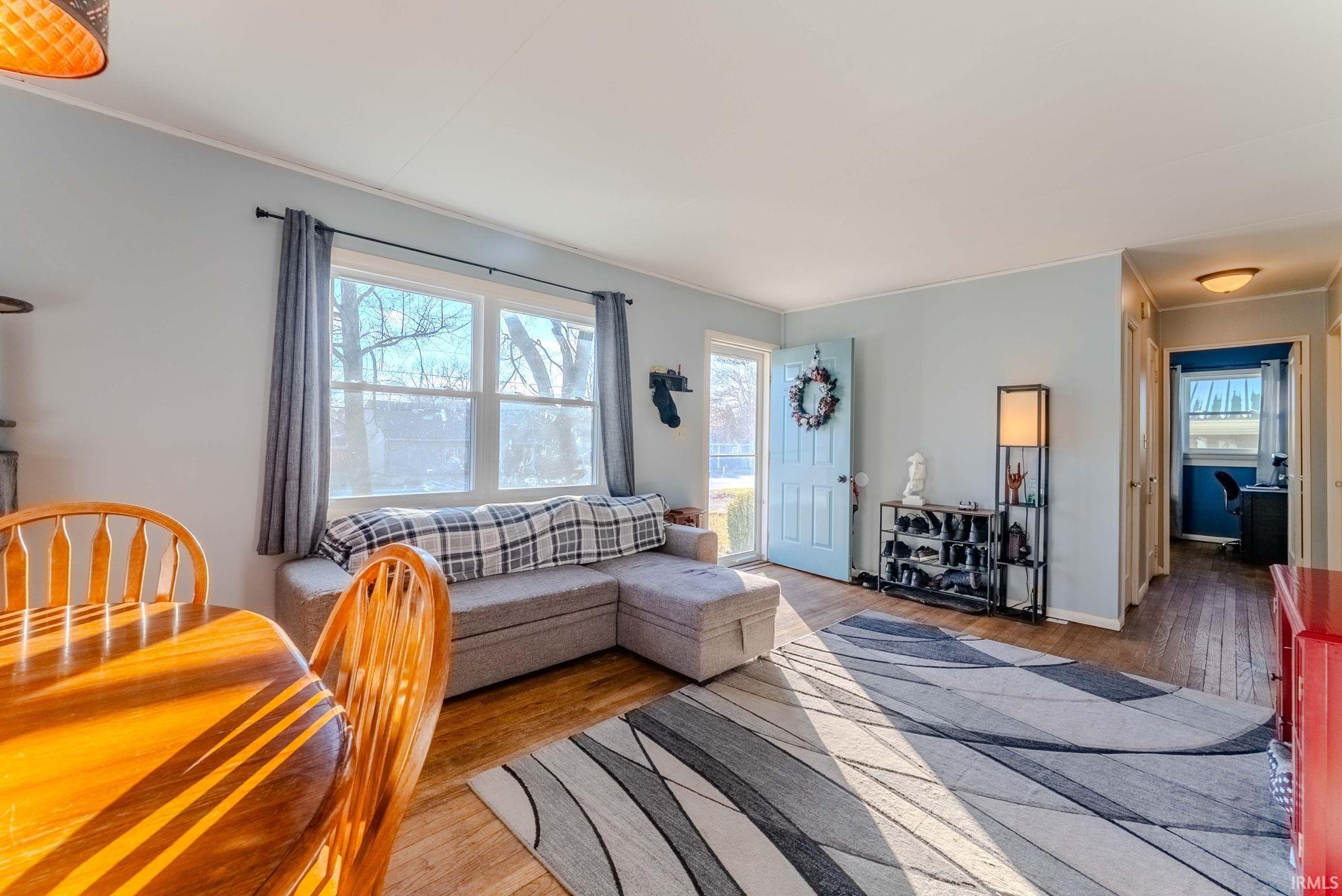 Living area with wood finished floors and ornamental molding