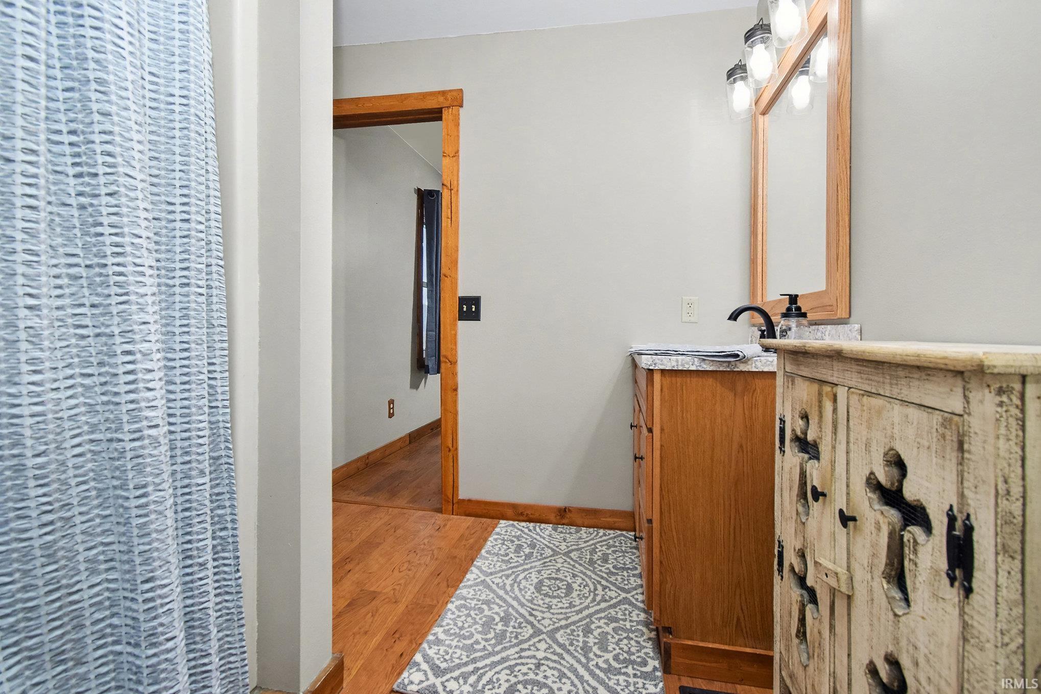 Bathroom featuring vanity, a heating unit, a shower with shower curtain, and light wood-style flooring