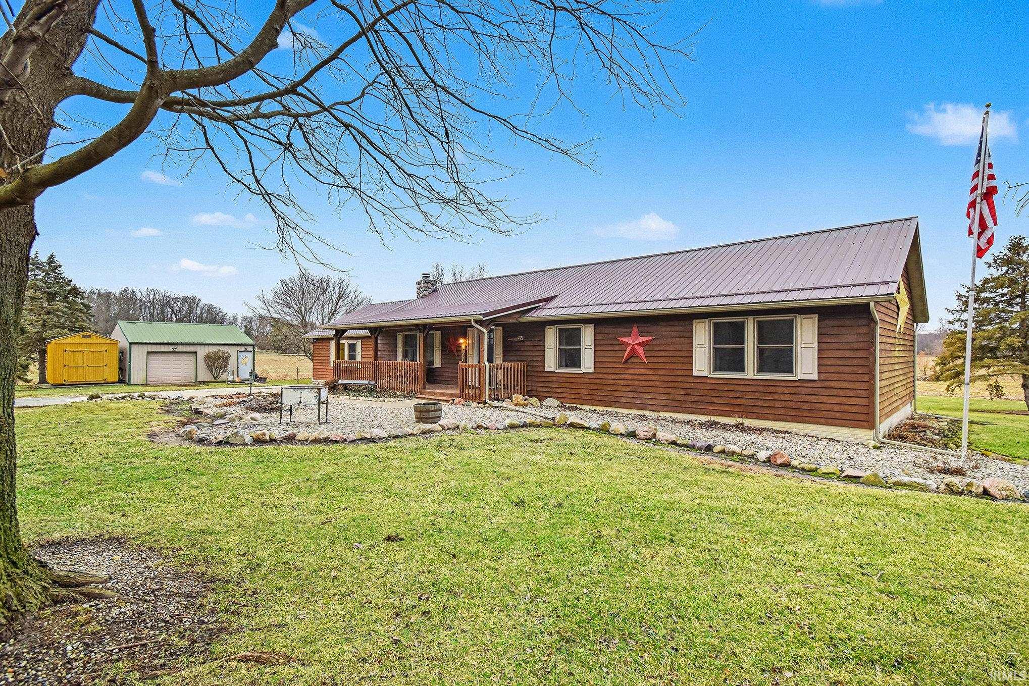 View of front of home featuring an outbuilding, a front lawn, and a metal roof