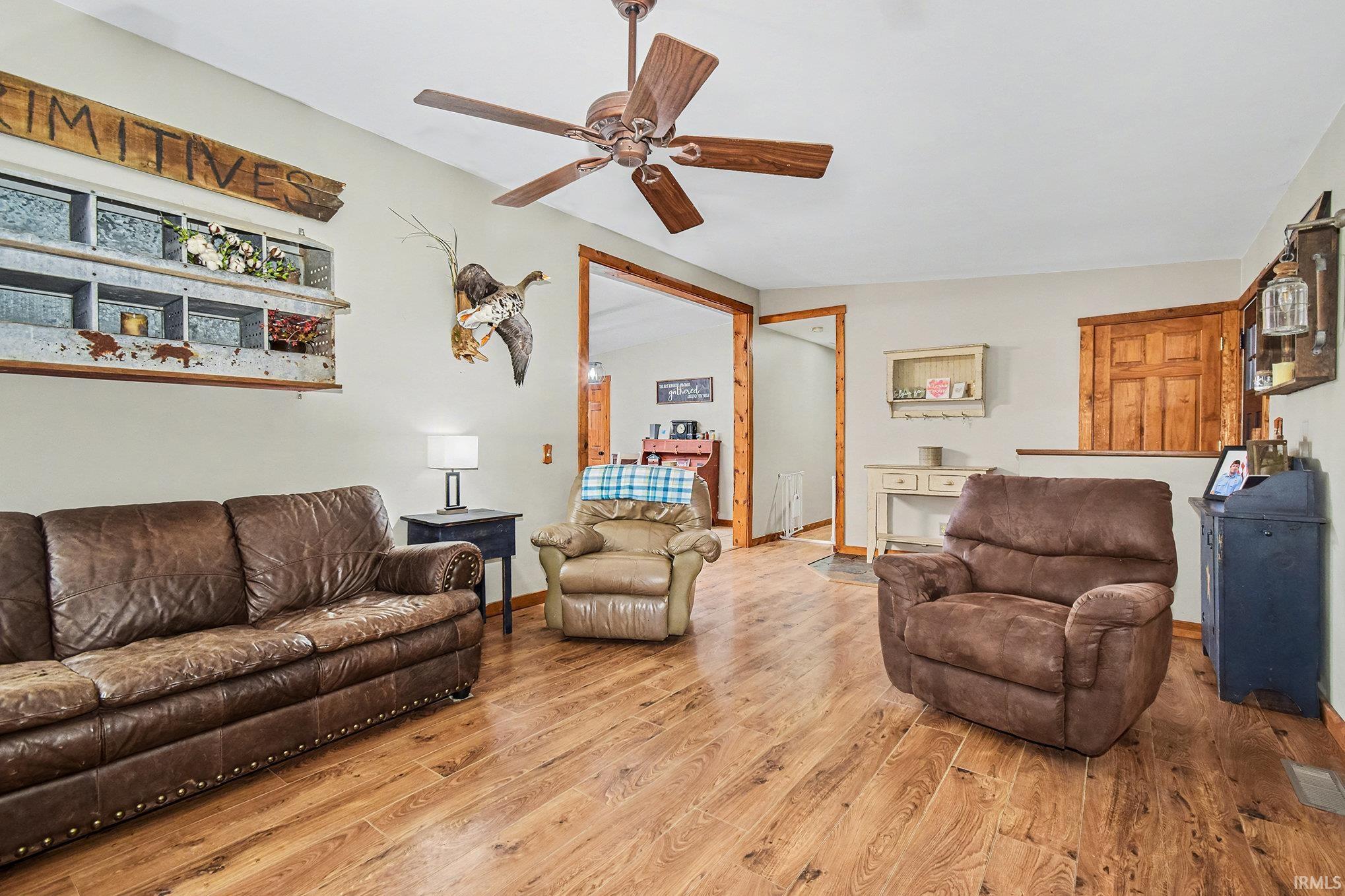 Living room featuring ceiling fan, hardwood / wood-style flooring, and vaulted ceiling
