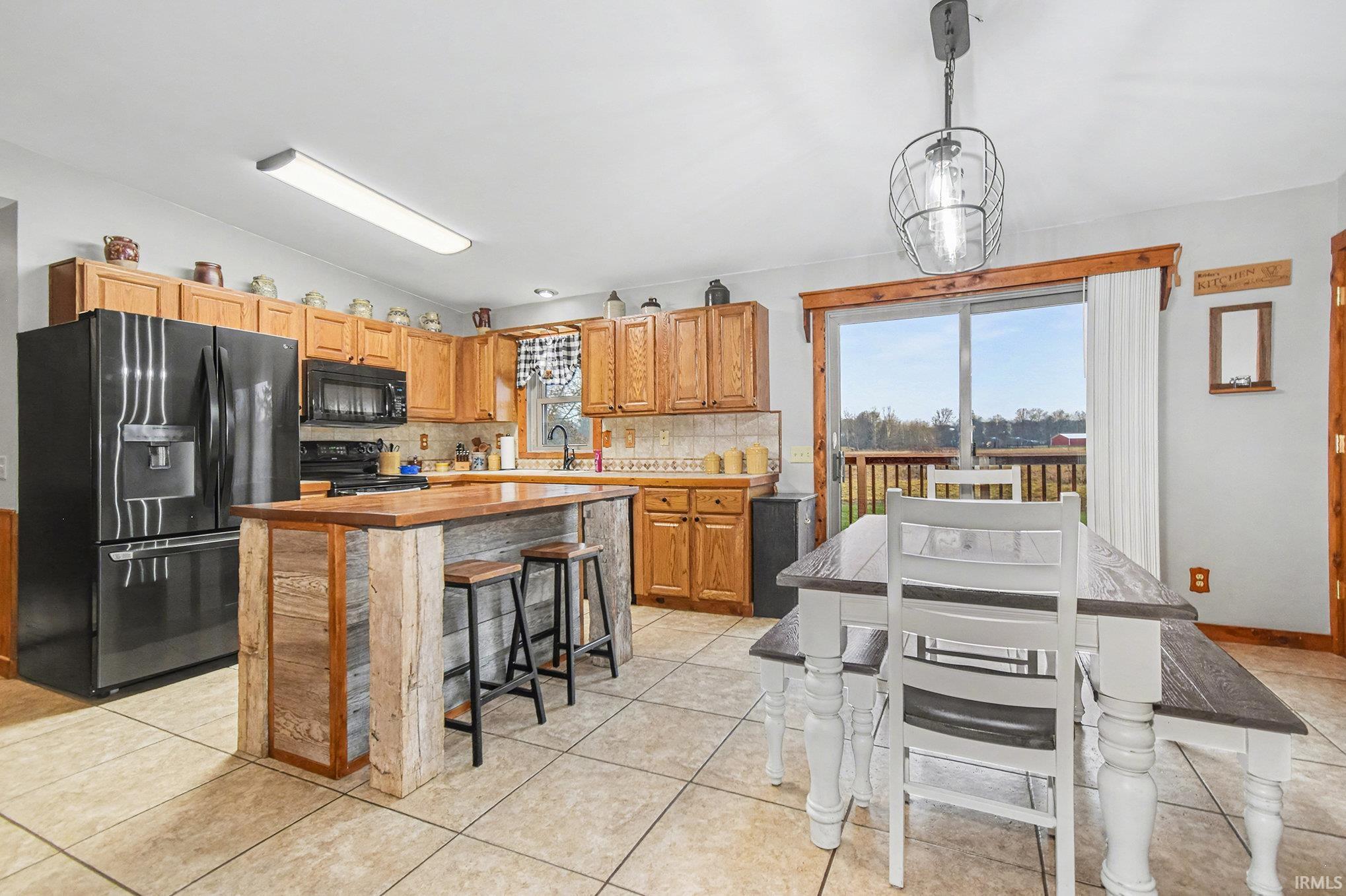 Kitchen with black appliances, lofted ceiling, a breakfast bar area, decorative backsplash, and pendant lighting