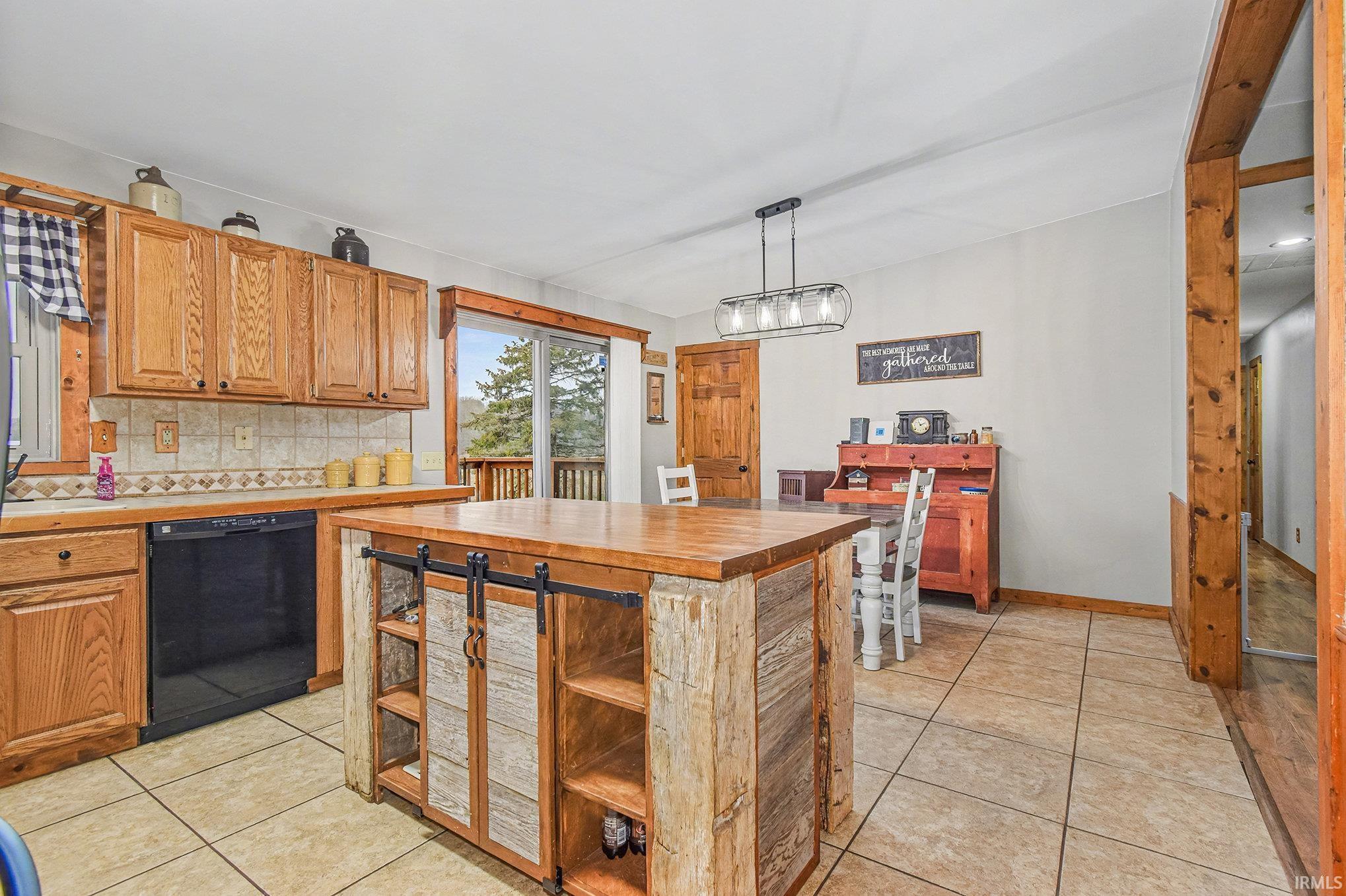 Kitchen with hanging light fixtures, dishwasher, brown cabinetry, and decorative backsplash