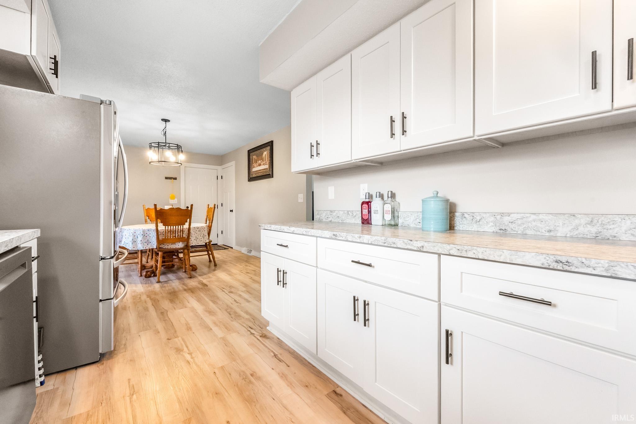 Kitchen featuring stainless steel appliances, light countertops, white cabinetry, and light wood-type flooring
