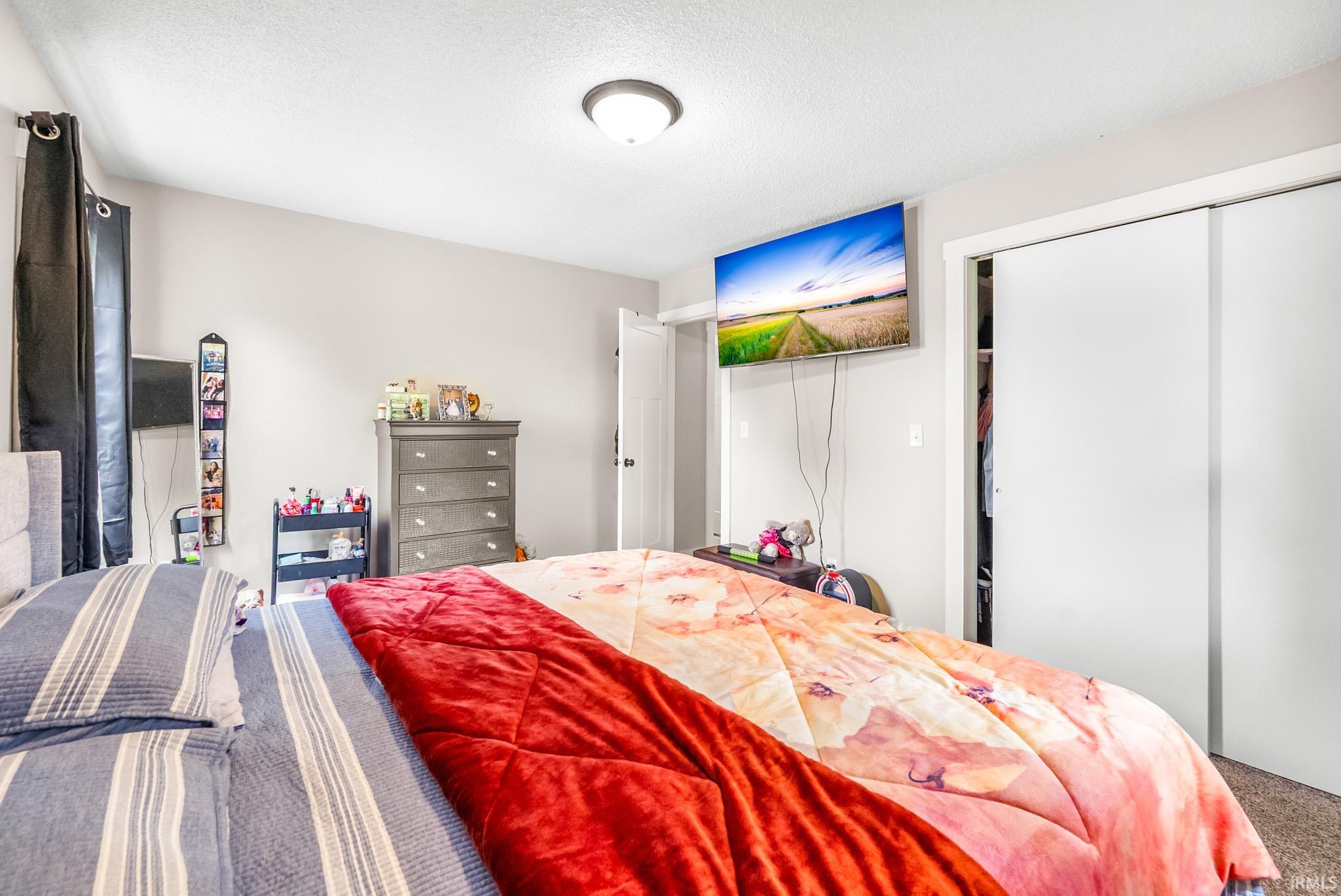 Bedroom with carpet floors, a closet, and a textured ceiling