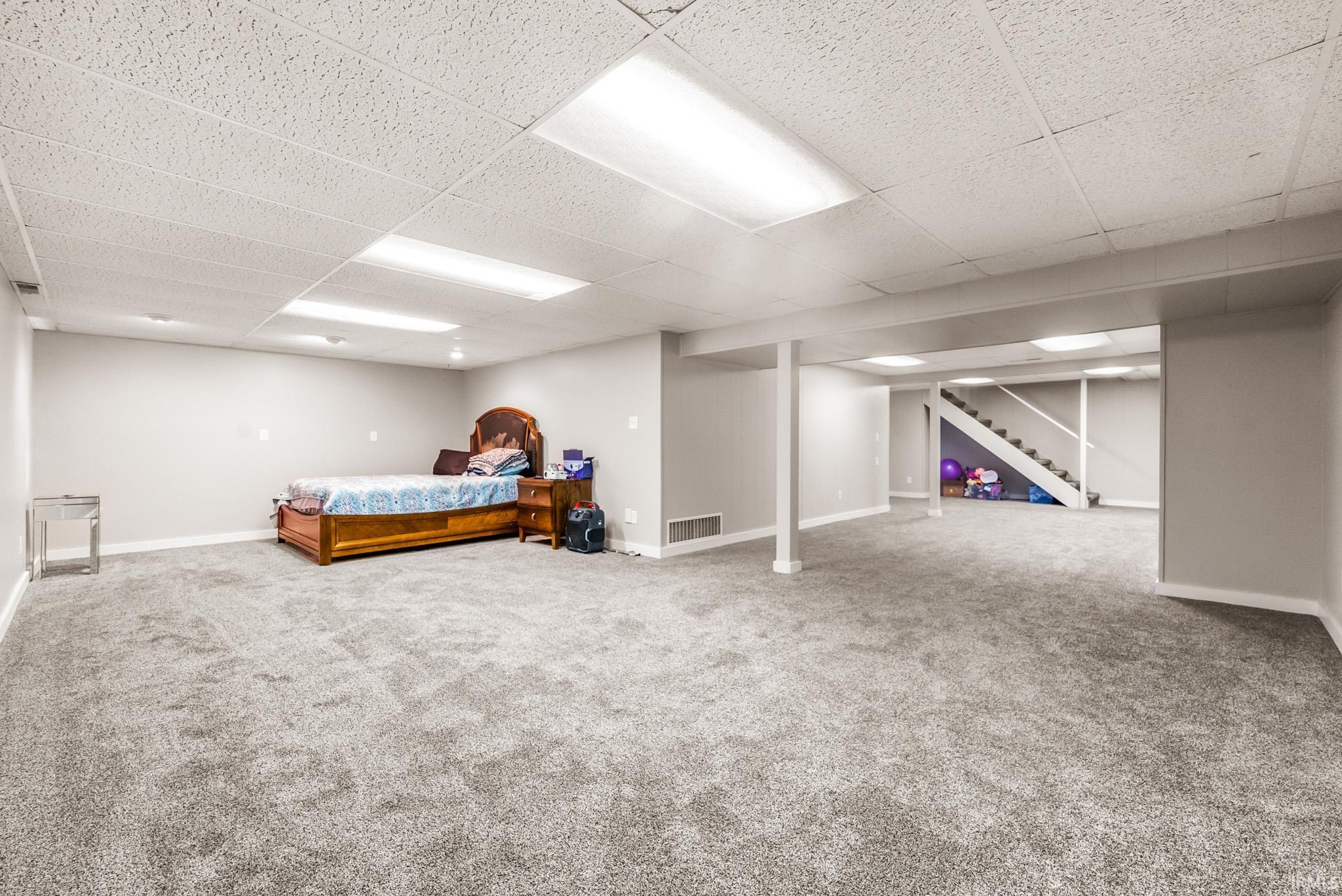 Bedroom with light colored carpet and a paneled ceiling