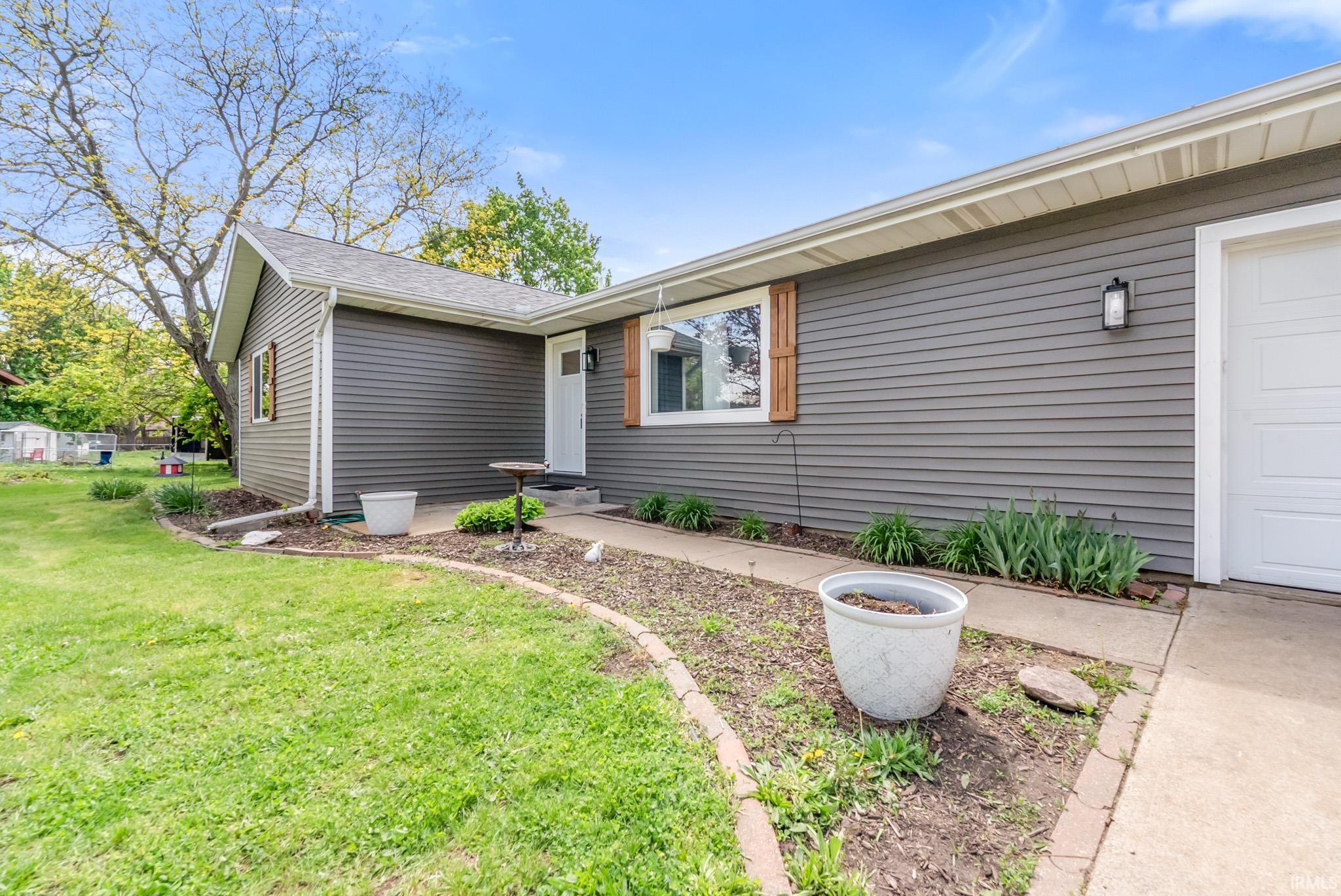 View of home's exterior with a lawn, a shingled roof, and a garage