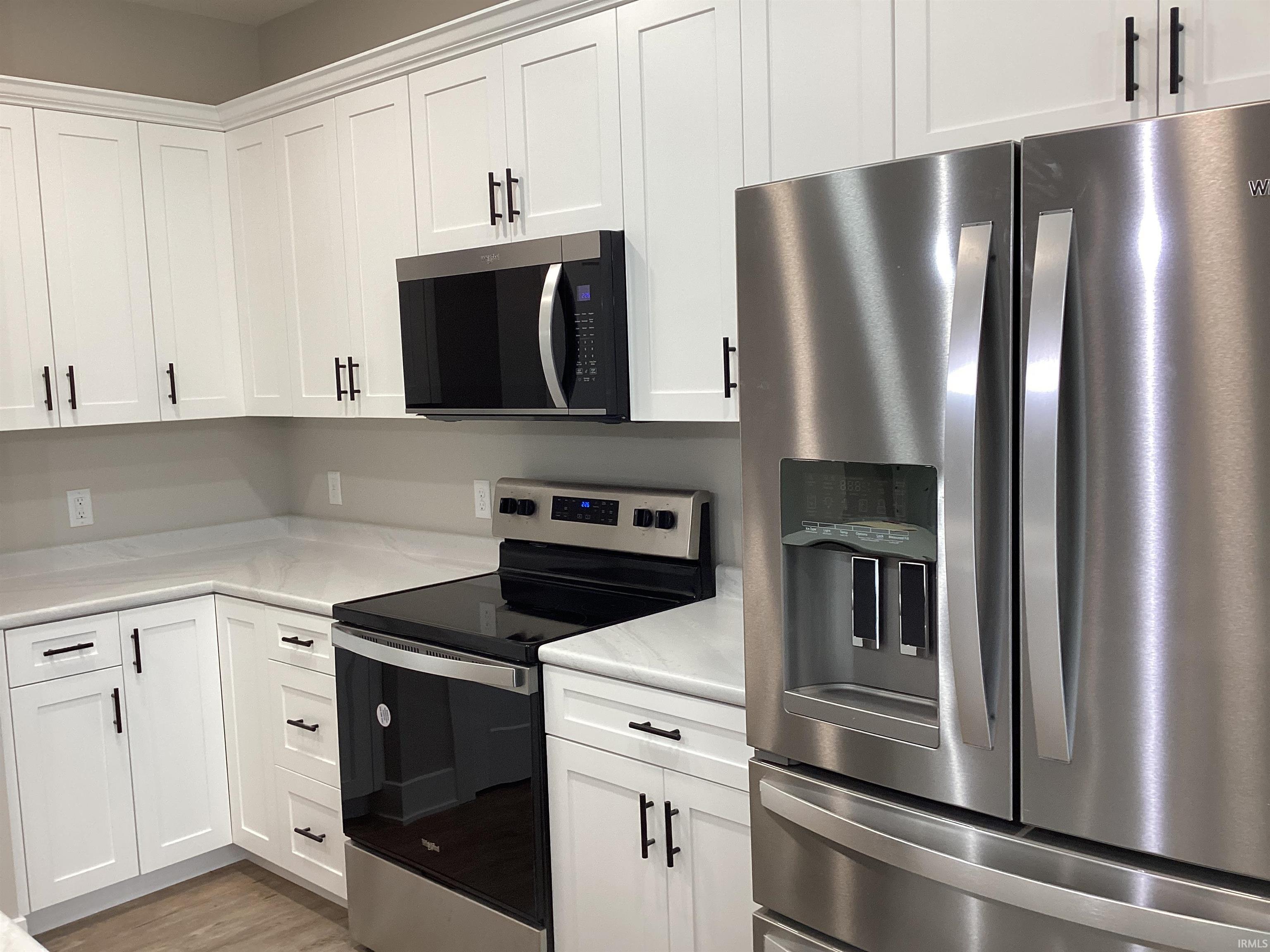 Kitchen with stainless steel appliances, white cabinets, and light wood-type flooring