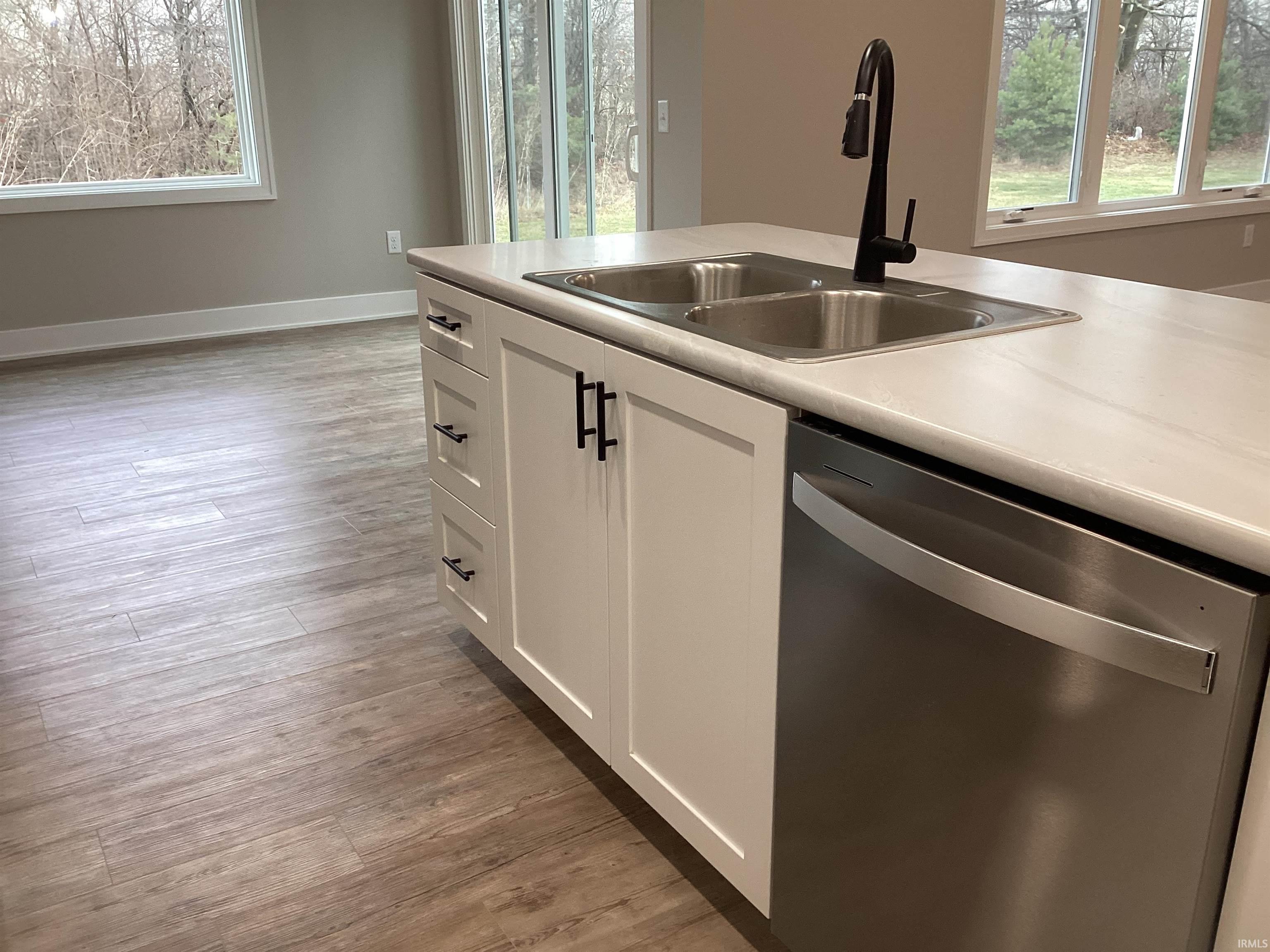 Kitchen with dishwasher, light wood finished floors, white cabinetry, and plenty of natural light
