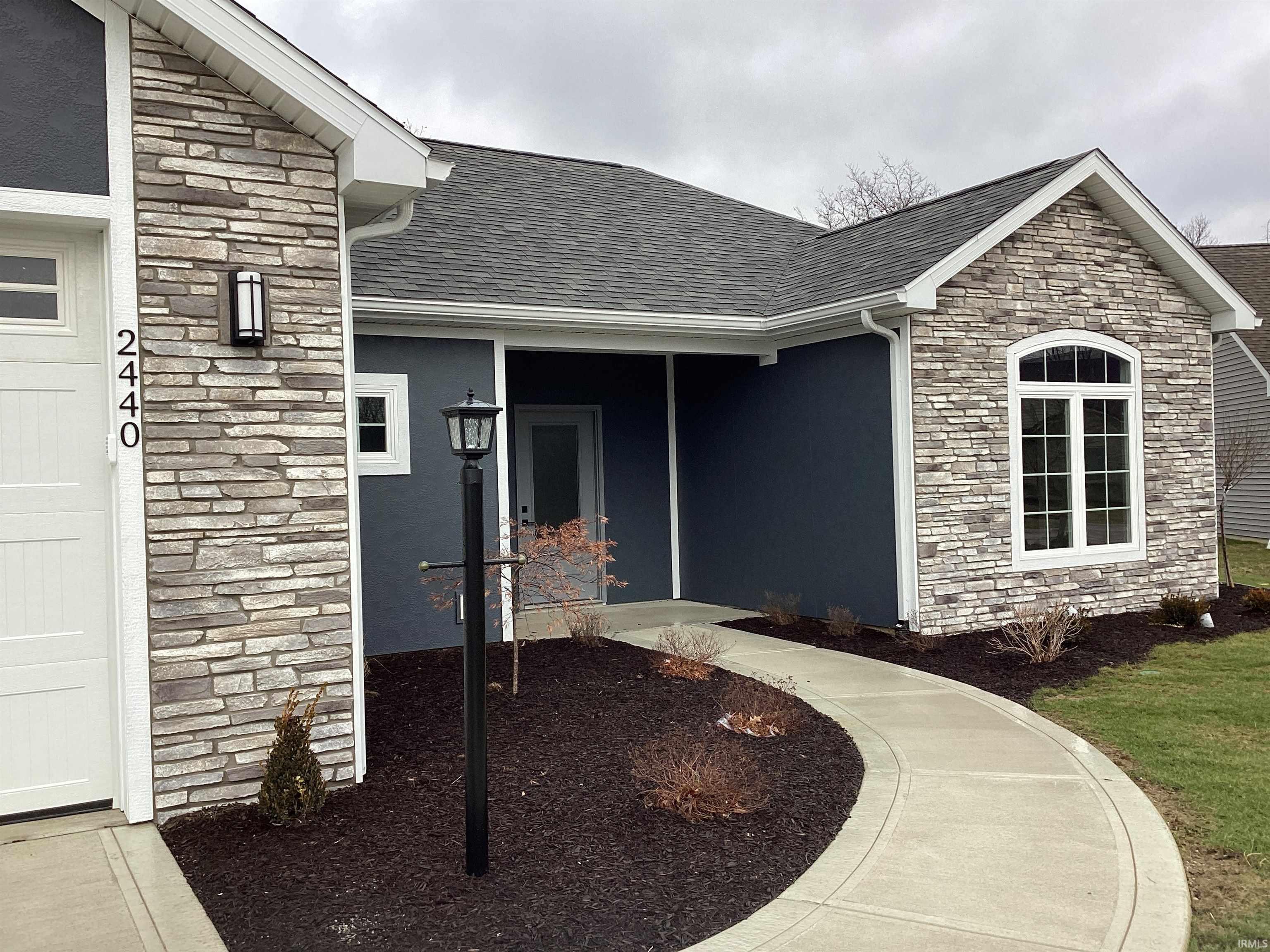 Doorway to property featuring stone siding, a shingled roof, stucco siding, and a porch