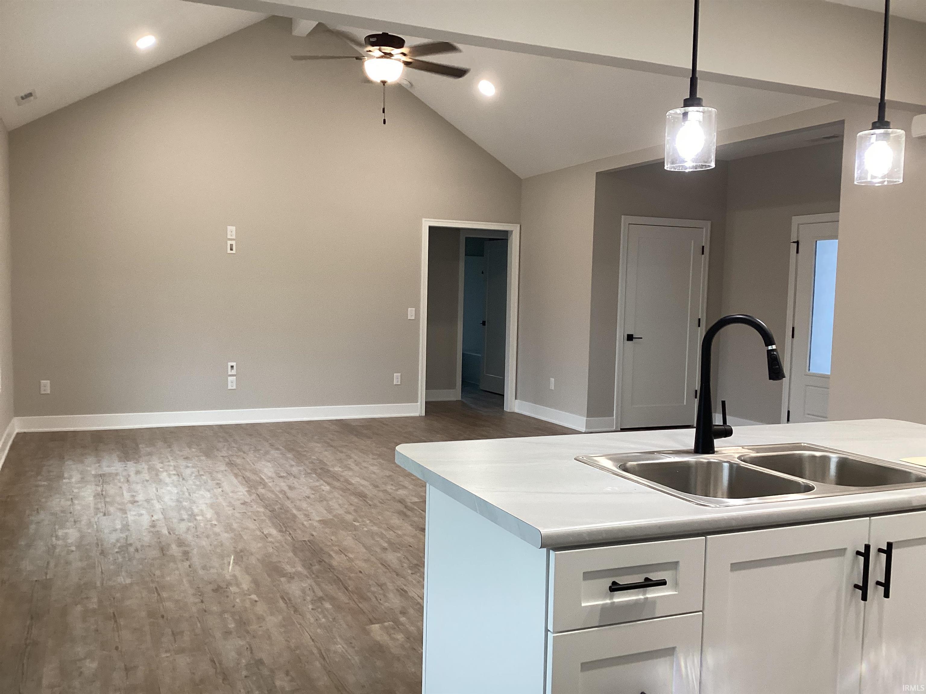 Kitchen featuring white cabinetry, decorative light fixtures, light countertops, open floor plan, and ceiling fan