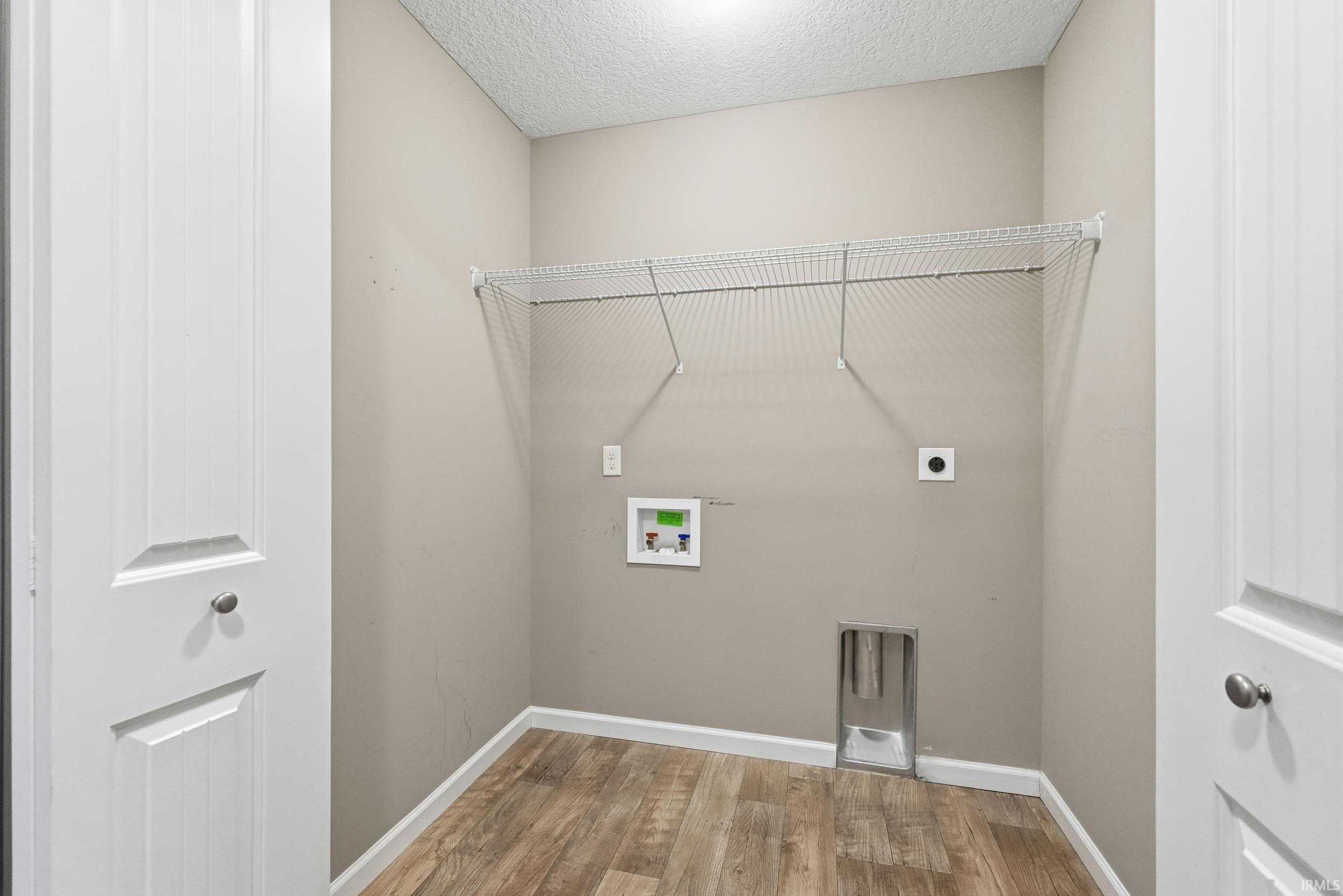 Washroom featuring hookup for a washing machine, wood finished floors, hookup for an electric dryer, and a textured ceiling