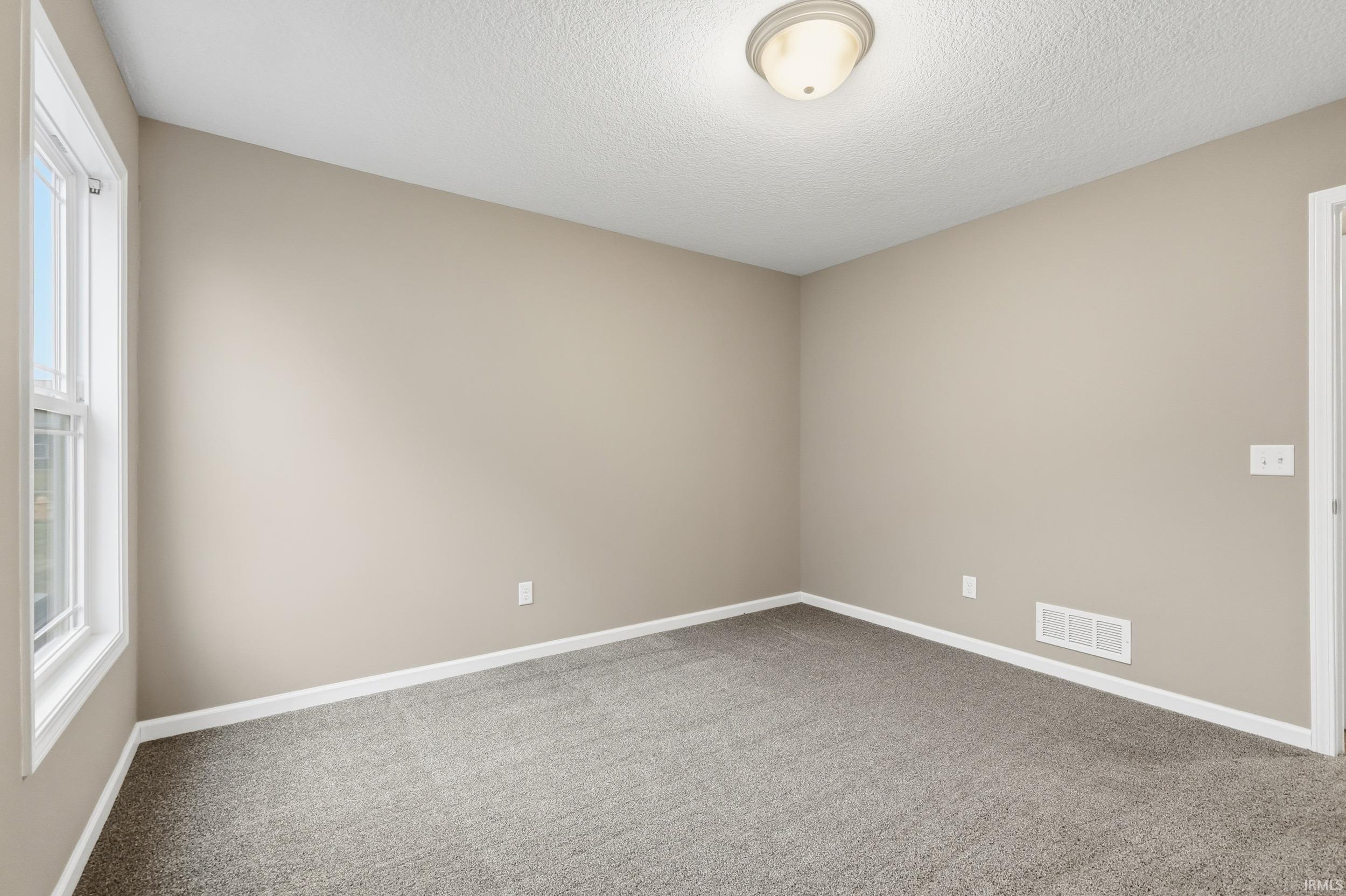 Empty room with carpet floors and a textured ceiling