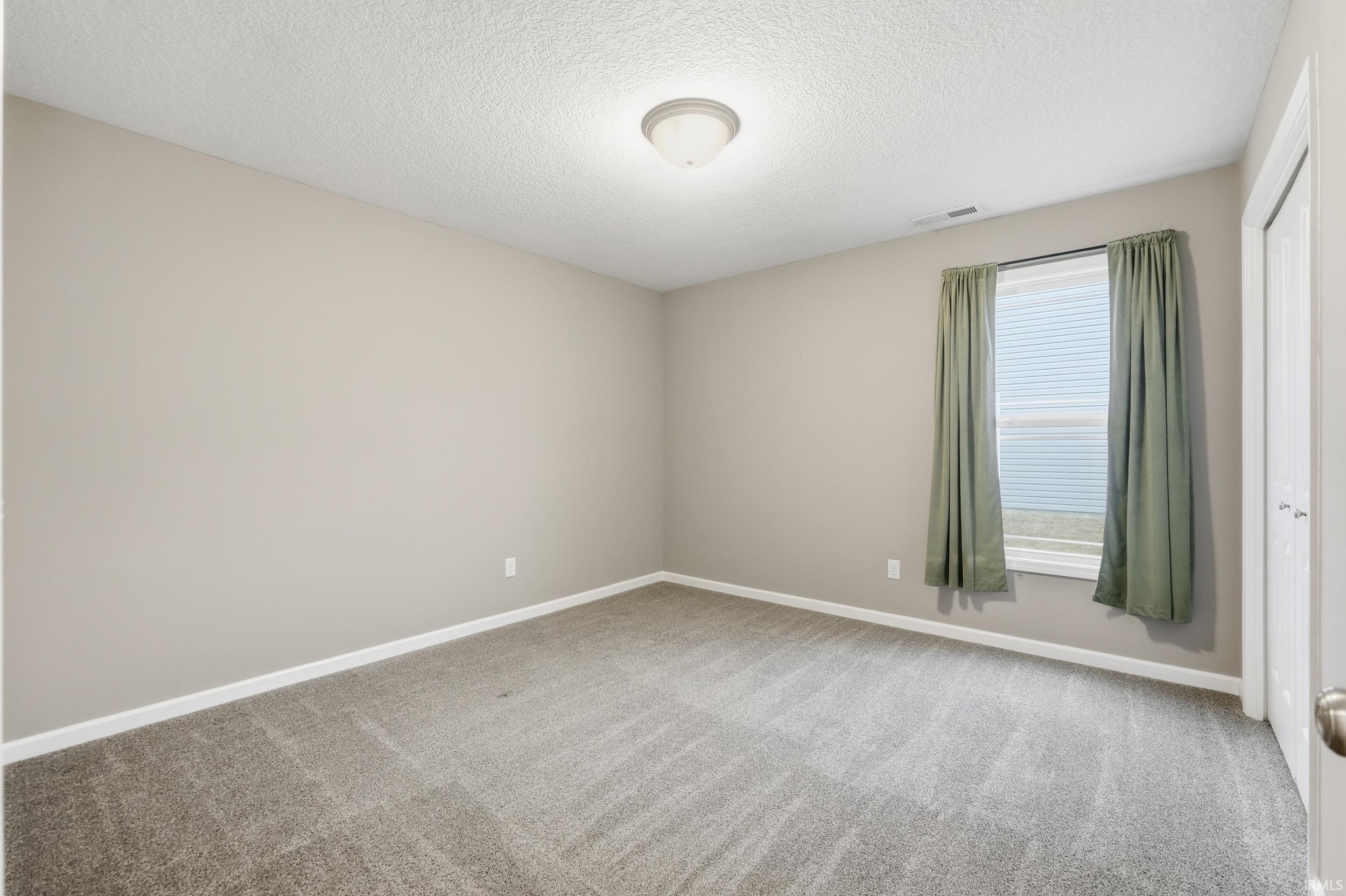 Unfurnished room with a textured ceiling and light carpet