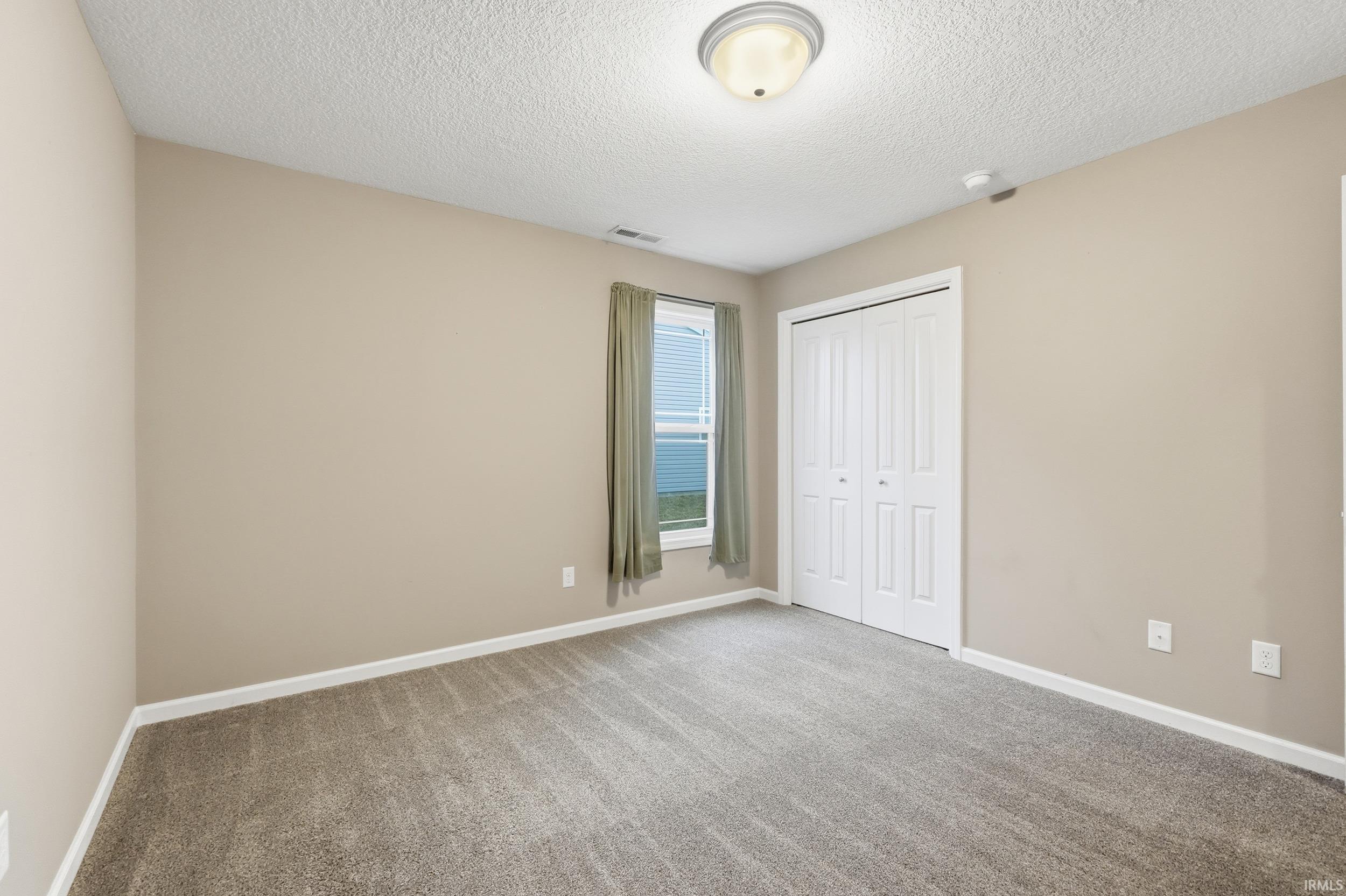 Unfurnished bedroom with carpet, a textured ceiling, and a closet