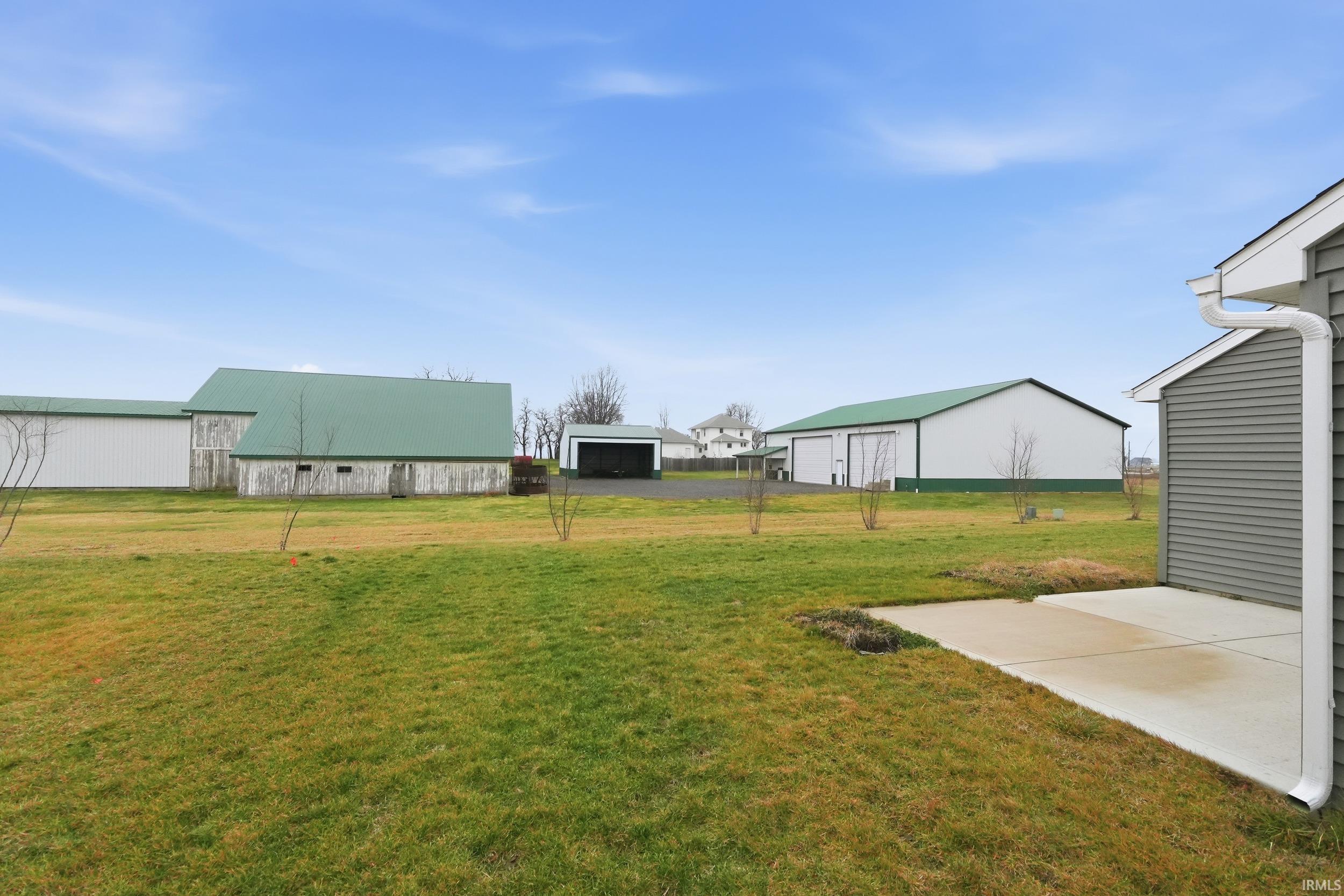 View of green lawn featuring an outbuilding and a garage