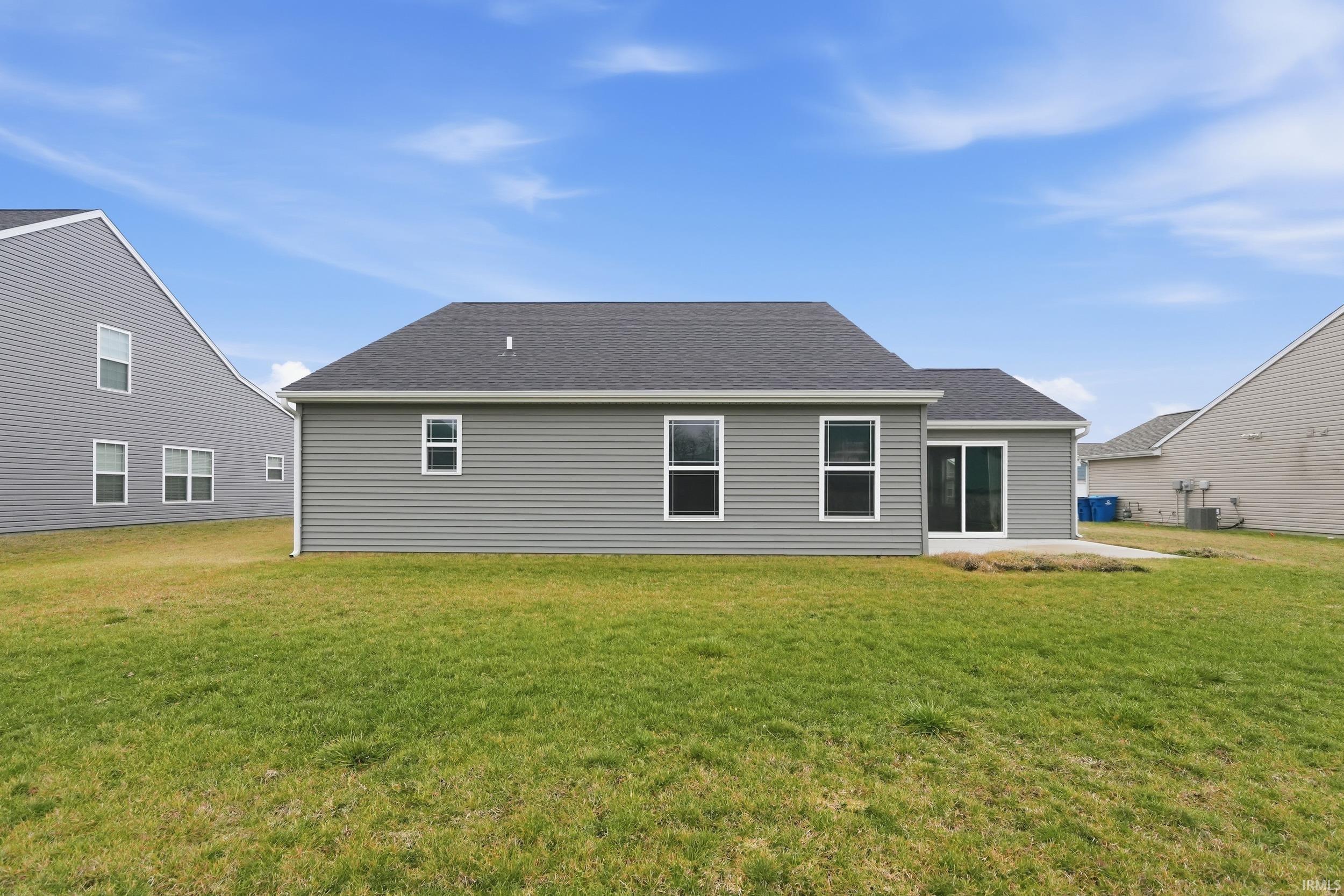 Rear view of property featuring a yard and roof with shingles