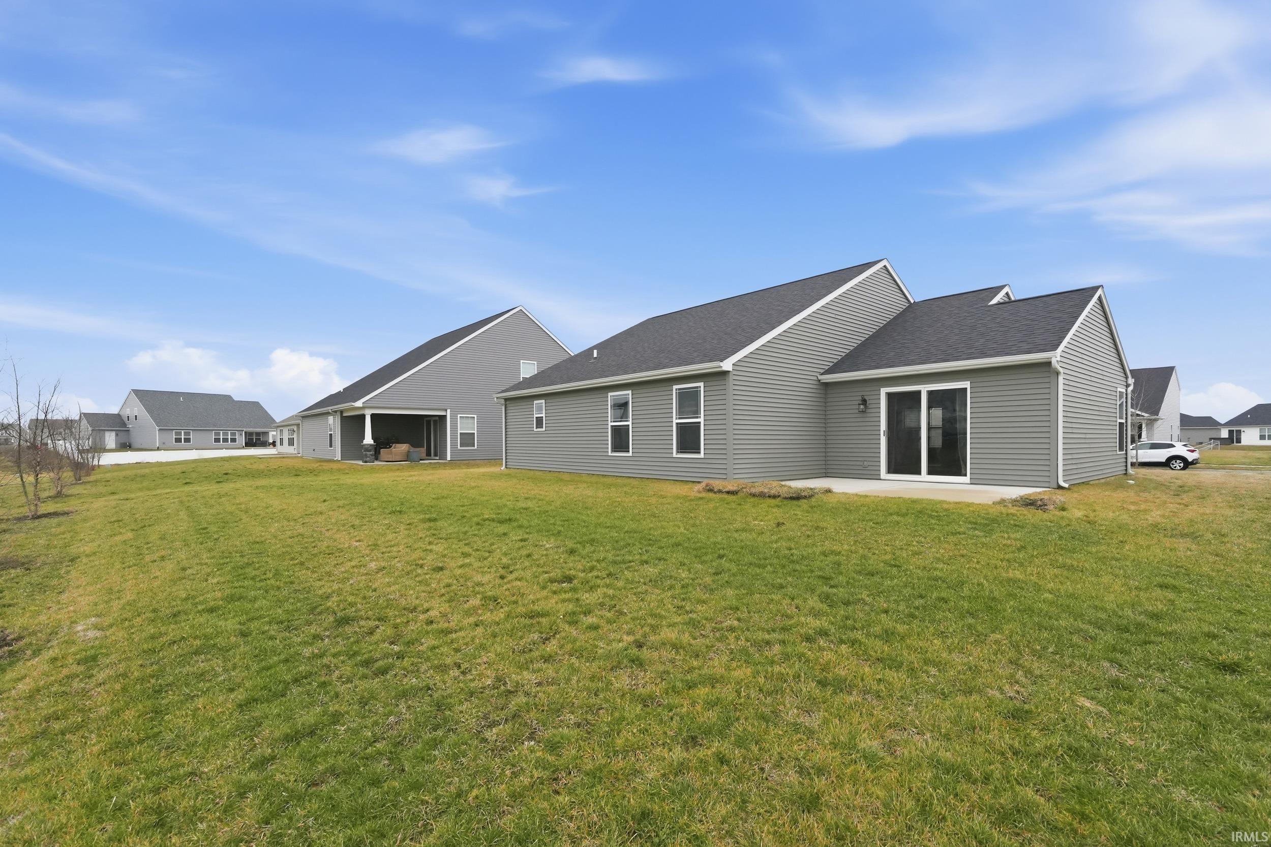 Back of house featuring a patio area, a yard, and a shingled roof