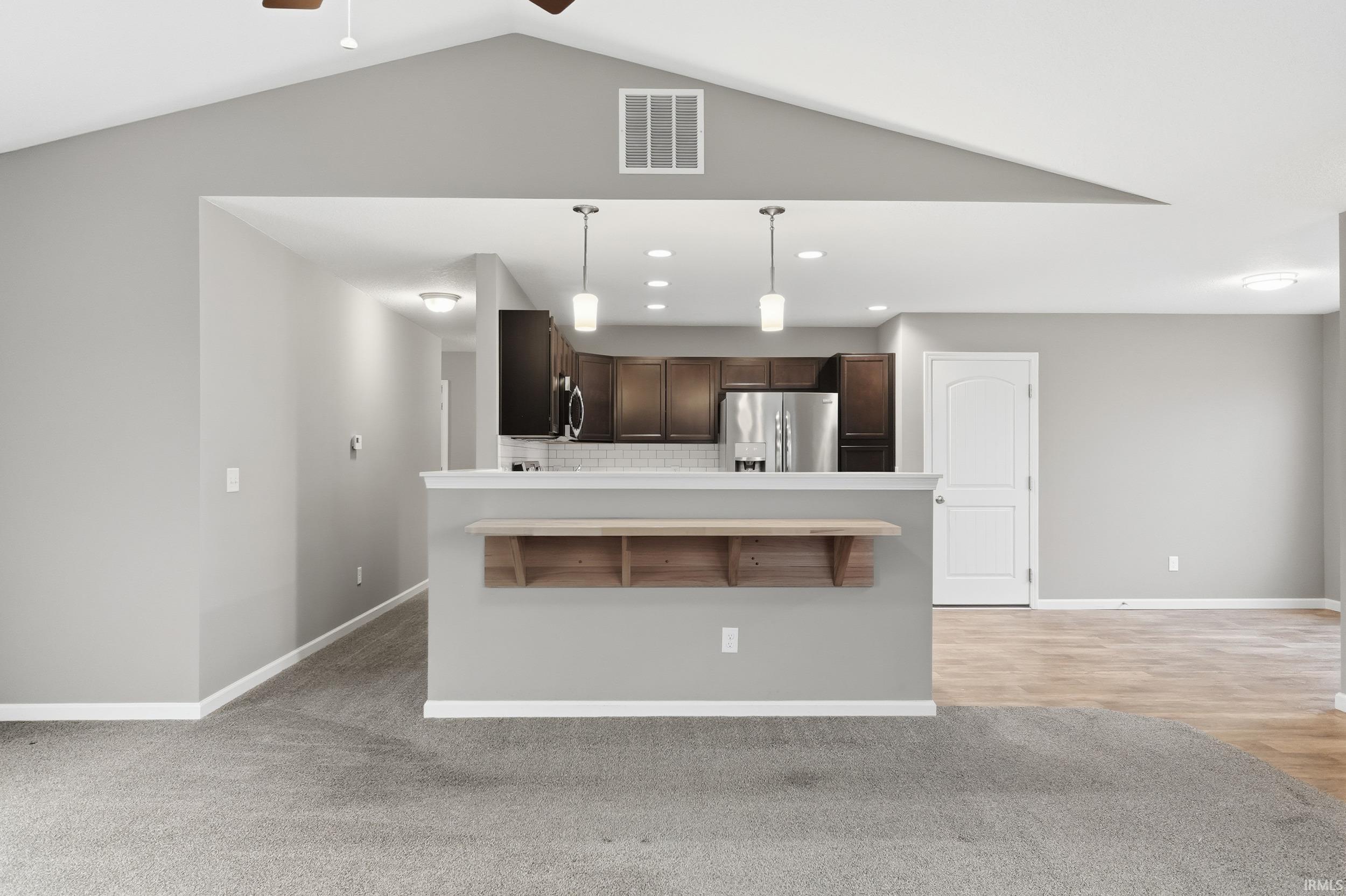 Kitchen with a peninsula, recessed lighting, dark brown cabinetry, hanging light fixtures, and light countertops