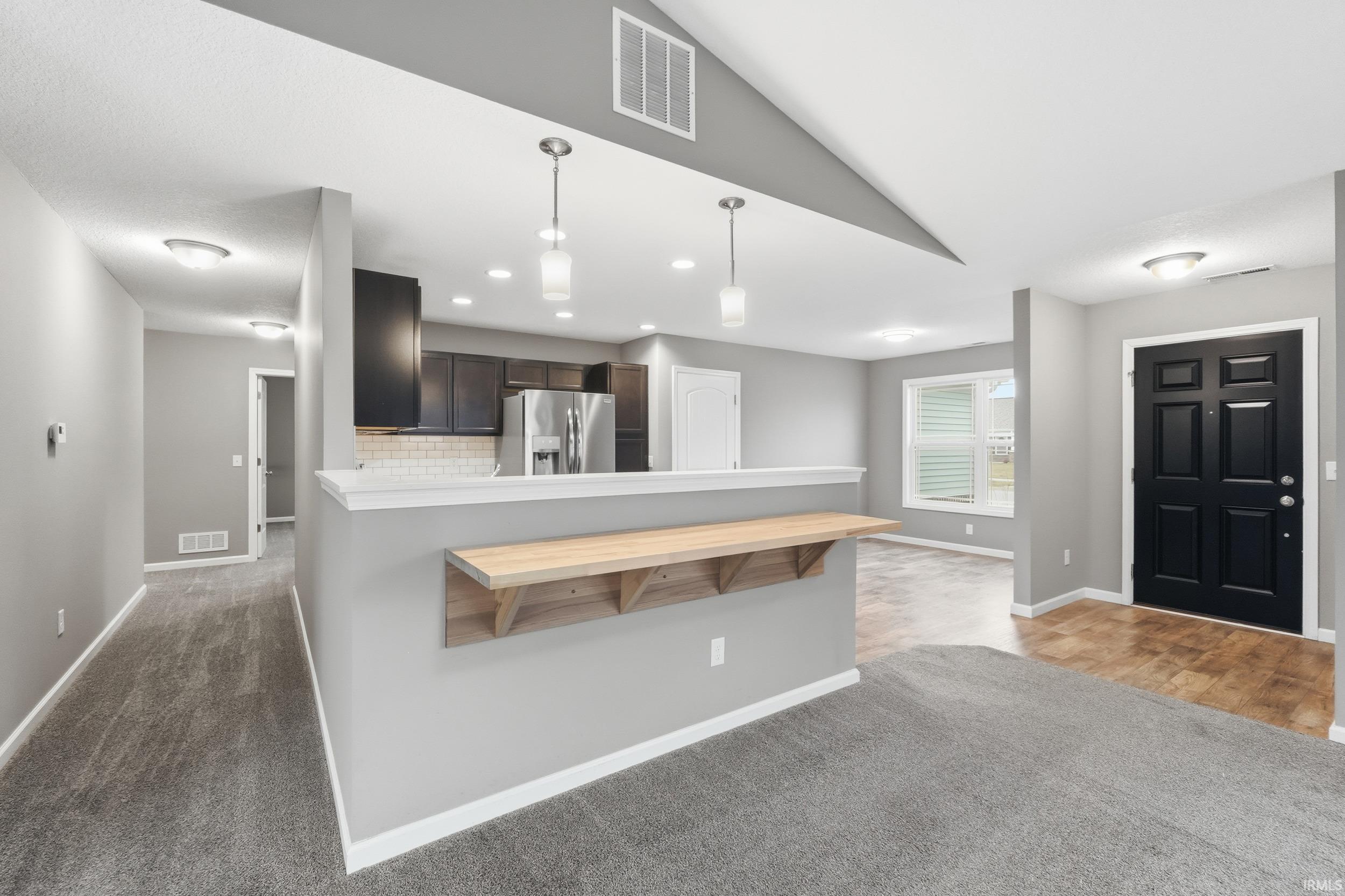 Kitchen featuring a peninsula, dark brown cabinets, light countertops, pendant lighting, and recessed lighting