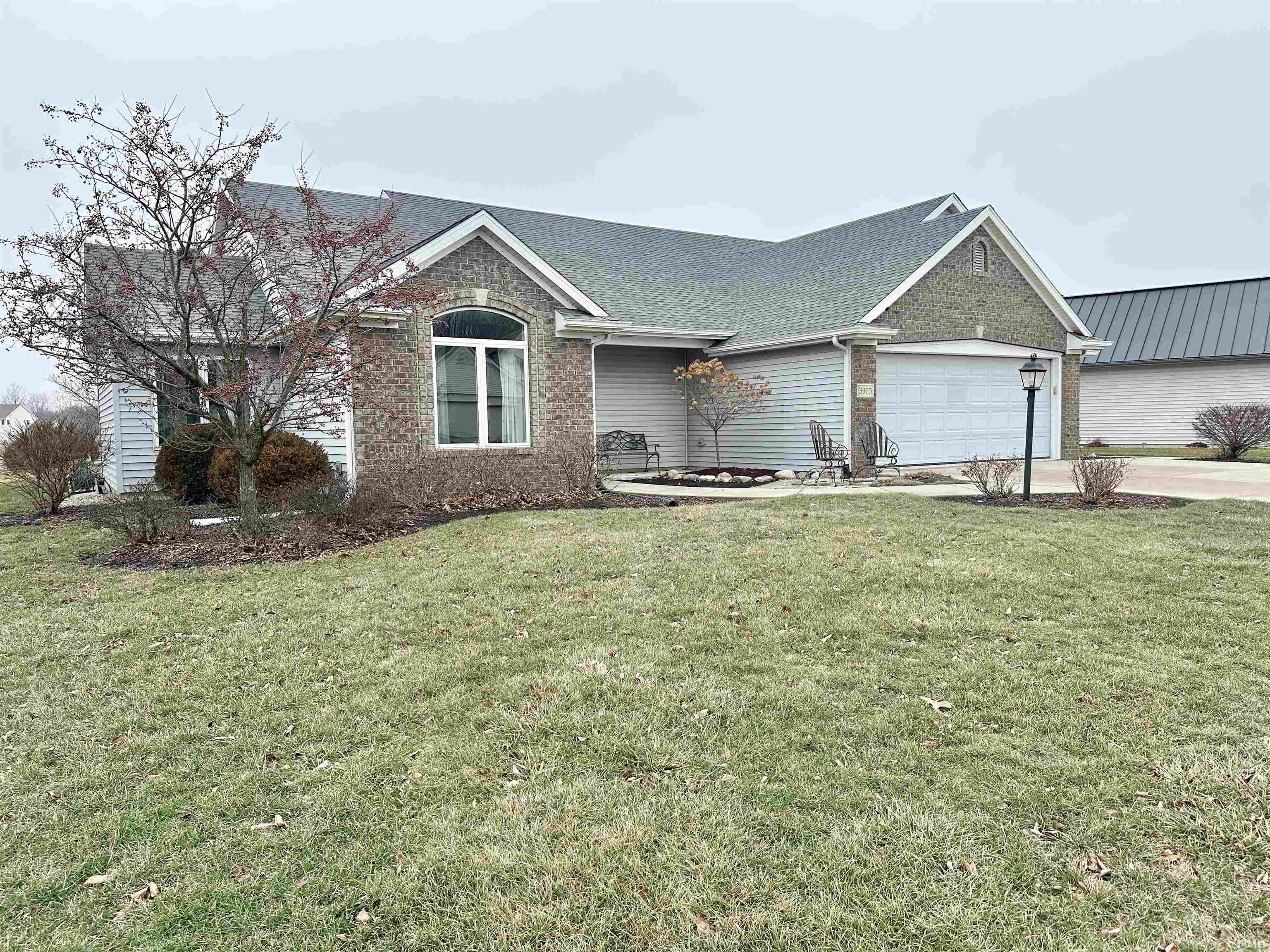 Single story home with brick siding, a shingled roof, a front yard, driveway, and a garage