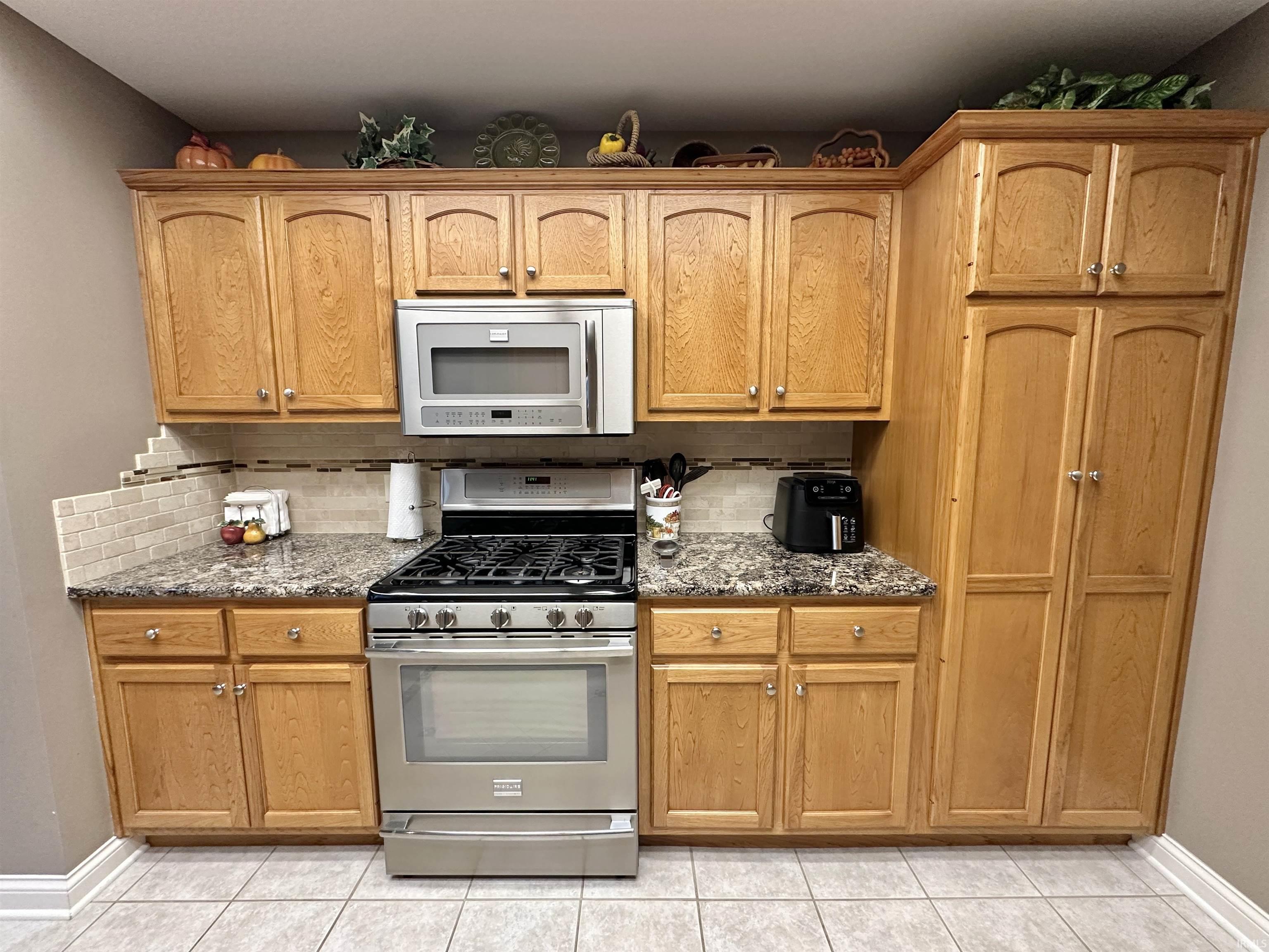 Kitchen featuring gas stove, dark stone counters, and tasteful backsplash