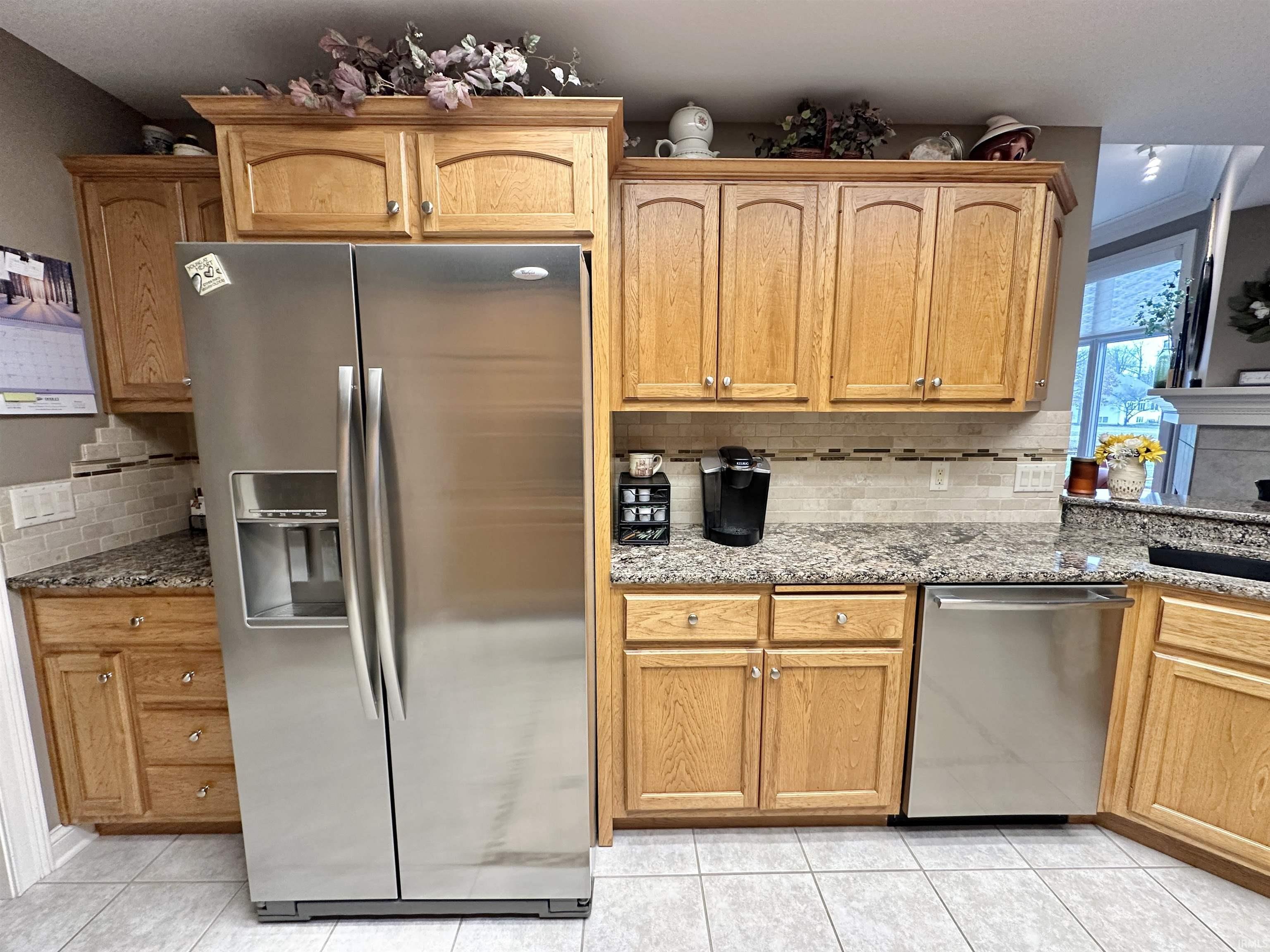 Kitchen with stainless steel appliances, light stone counters, and decorative backsplash