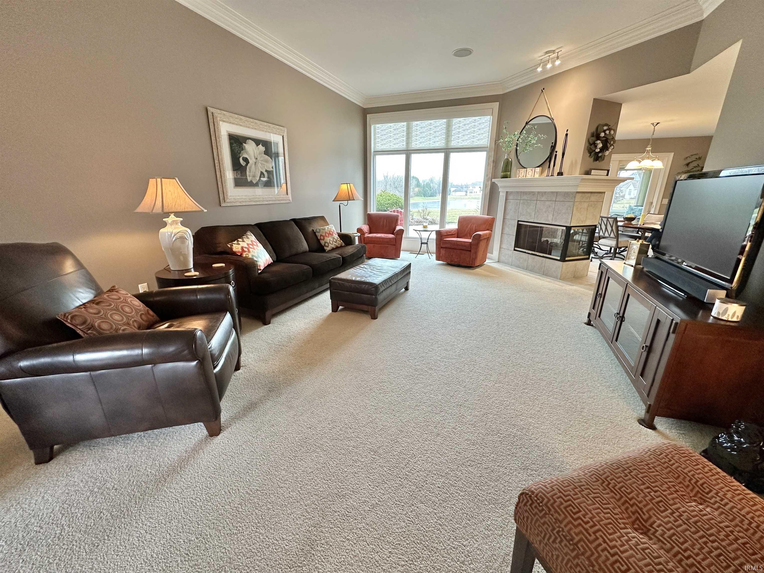 Living room with light colored carpet, a tile fireplace, and crown molding