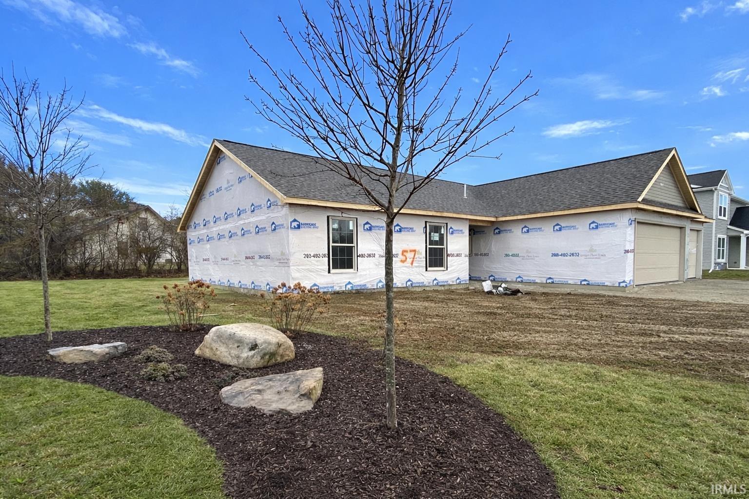 Property under construction with a garage, a front yard, and a shingled roof